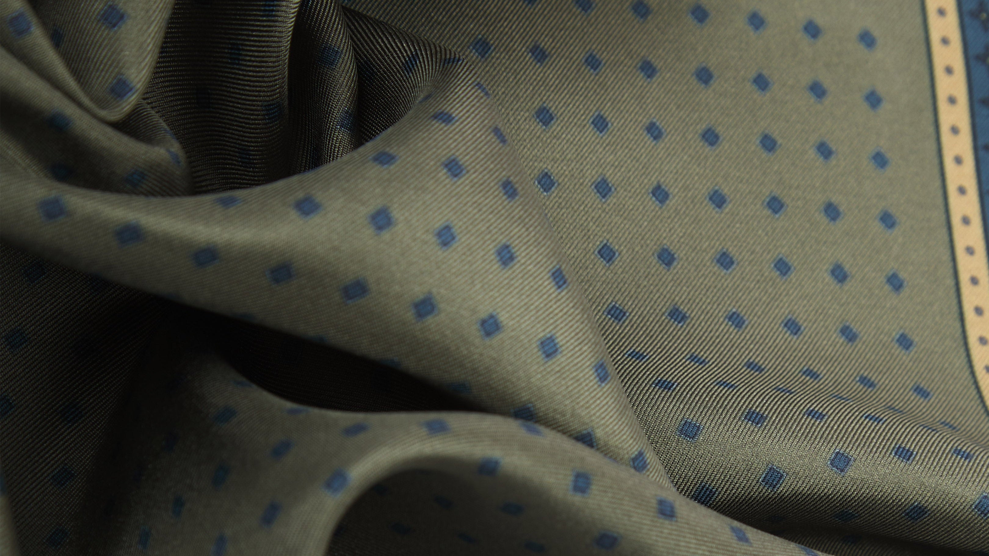 Close-up of green fabric with blue polka dots and beige border