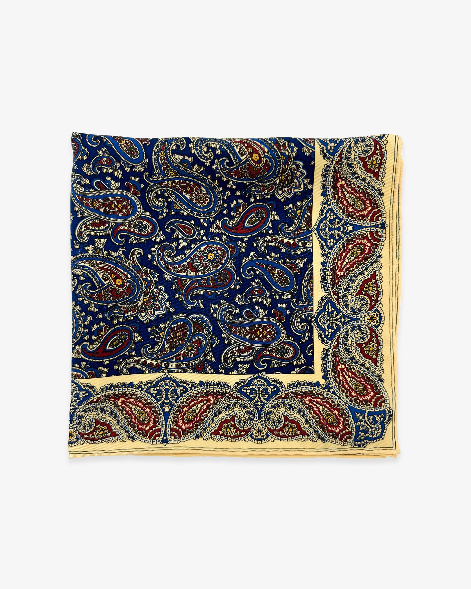 The 'Abbotsbury' pocket square from SOHO Scarves Madder silk collection. Folded into a quarter, showing the intricate inner and outer paisley decoration in blue, red and cream.