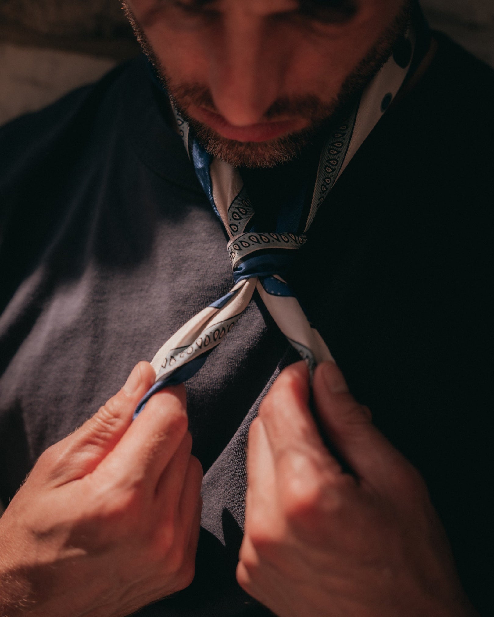 Close-up of man tying the 'Belgravia in Cream and Blue' silk neckerchief from SOHO Scarves.