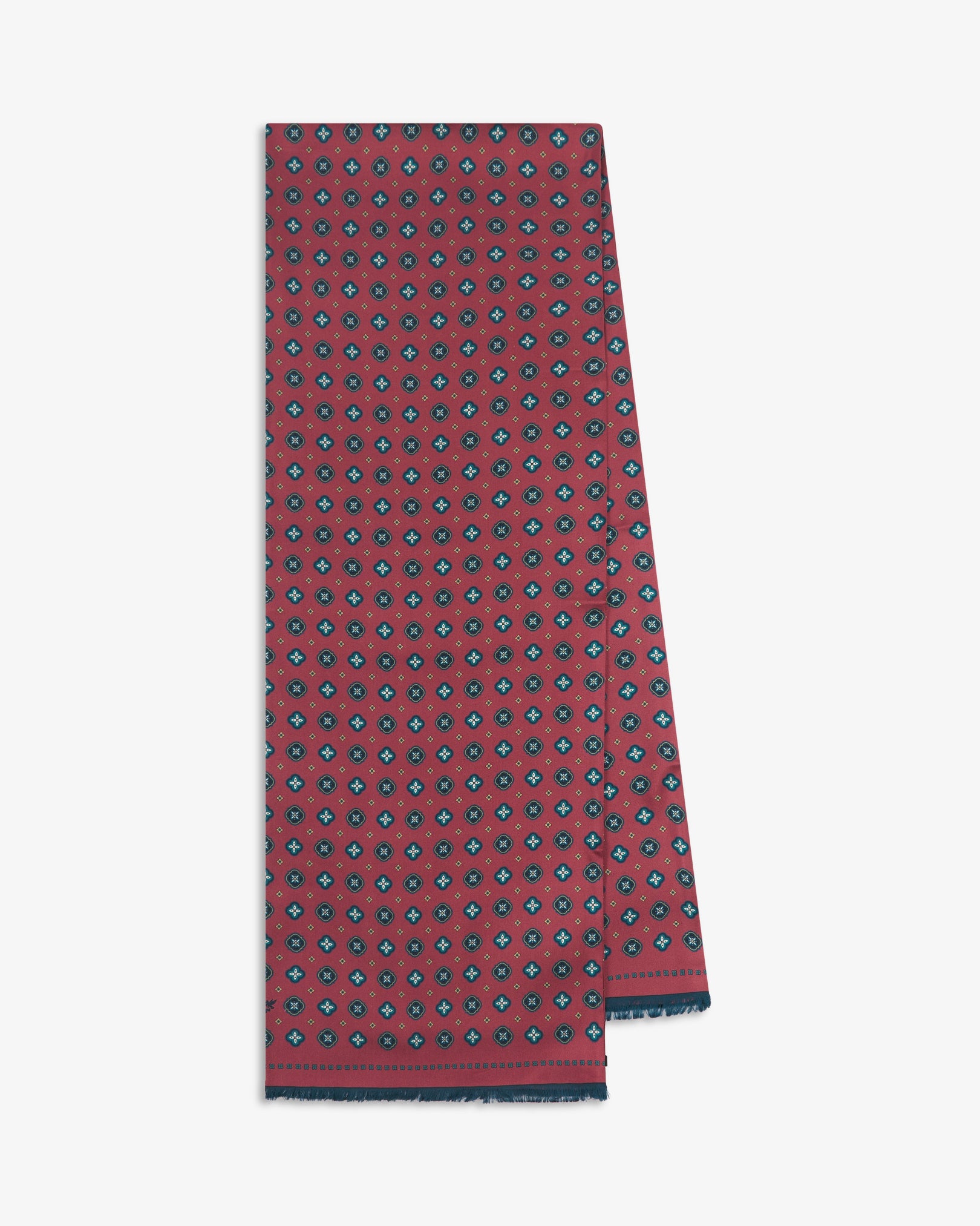 The 'Chelsea' silk scarf folded and presented vertically to showcase the full length of its repeating teal quatrefoil cross and circle medallion pattern on a deep crimson-berry ground, finished with a slim navy border and crafted in the UK from luxurious 16 momme silk twill.