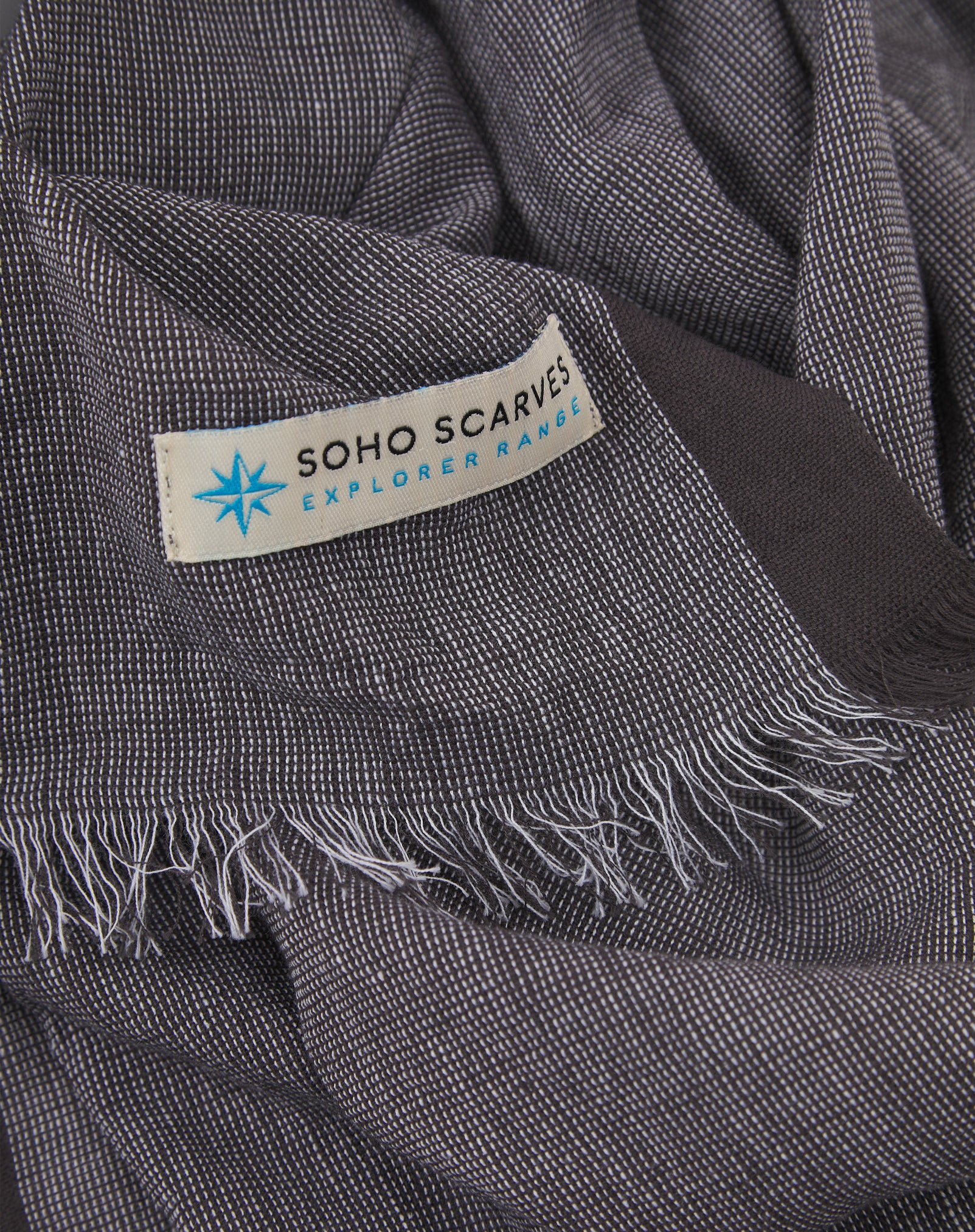 Ruffled close-up view of the pure cotton 'Messner' scarf, presenting a closer view of the brown yarns which make up the open-weave texture.