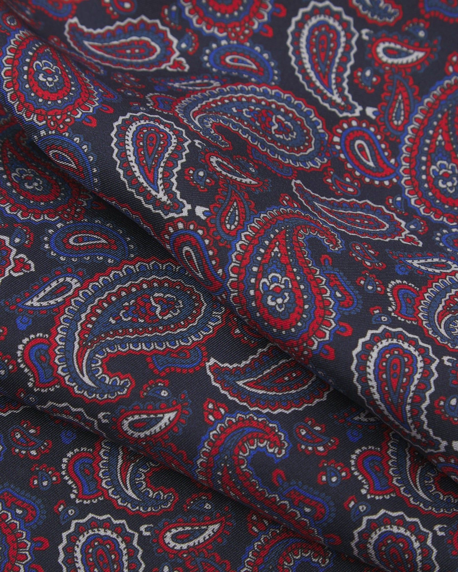 Ruffled close-up view of the Oakland silk scarf, presenting a closer view of the red, white and royal blue paisley patterns.