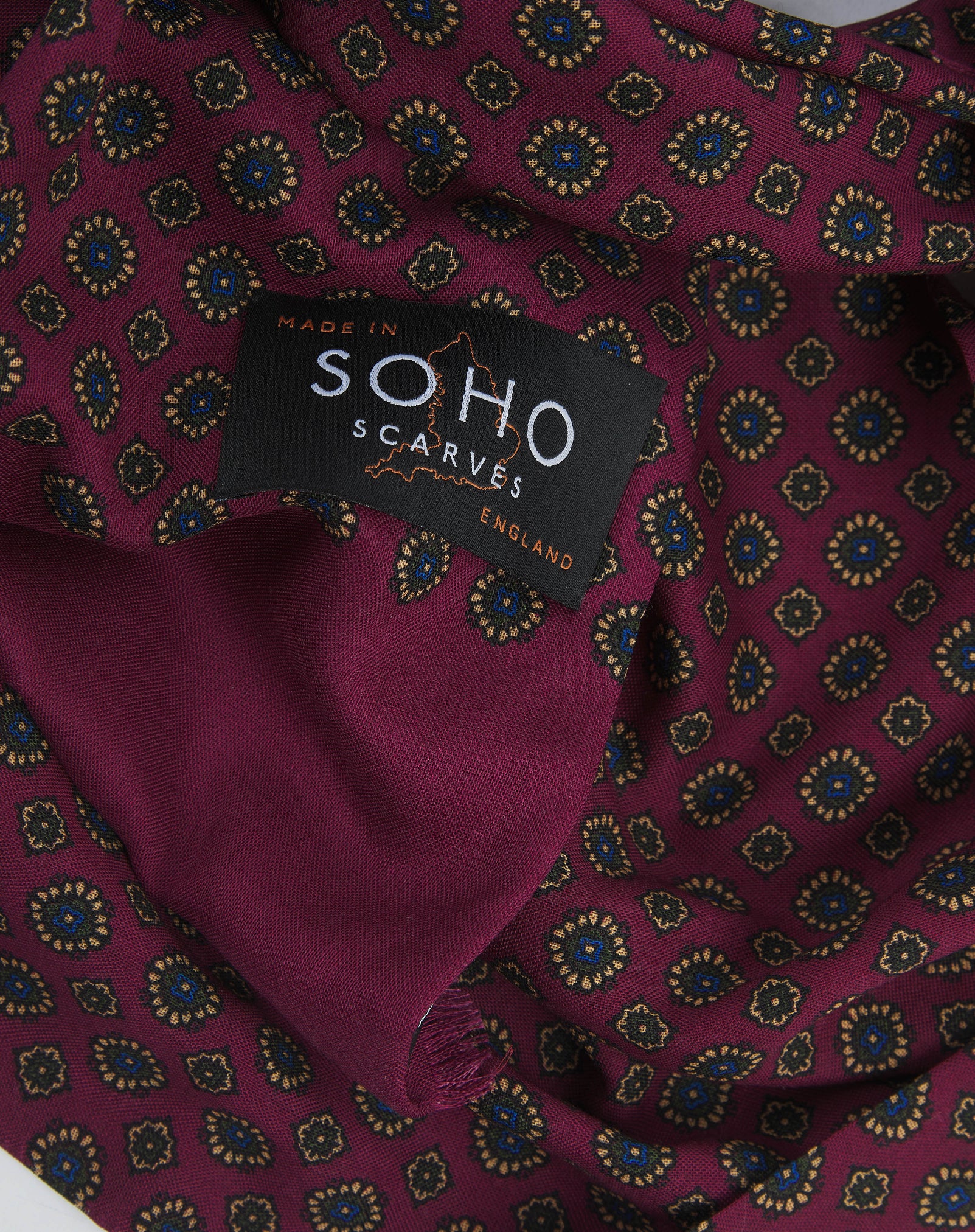 A ruffled, close-up view of the UK-made magenta and royal blue silk and wool scarf adorned with yellow and blue floral-inspired repeat patterns. Clearly showing the premium silk and wool weave.