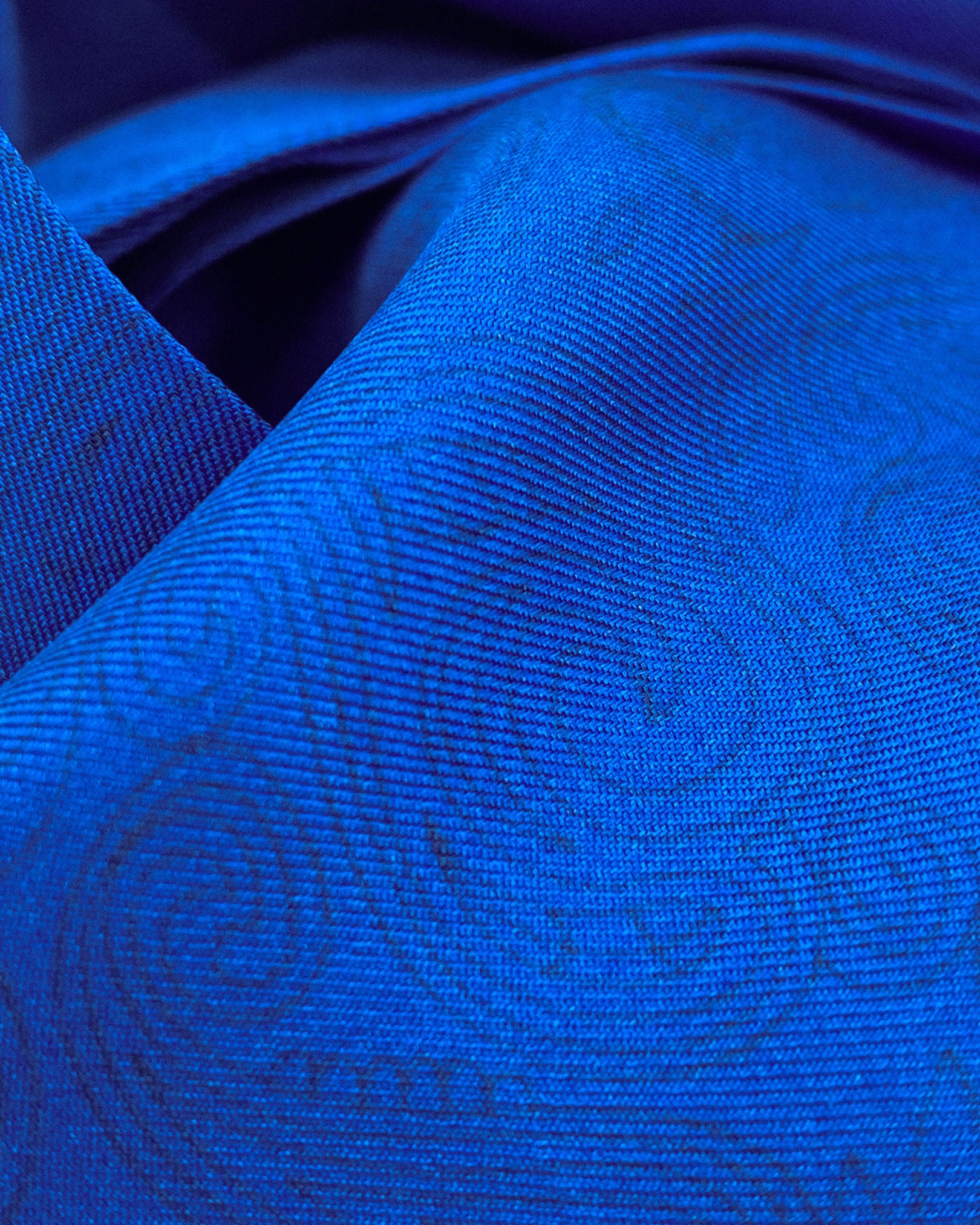 Ruffled close-up view of the 'Adachi ' silk aviator scarf, presenting a closer view of the powder-blue paisley swirls and subtle lustre of the silk material.