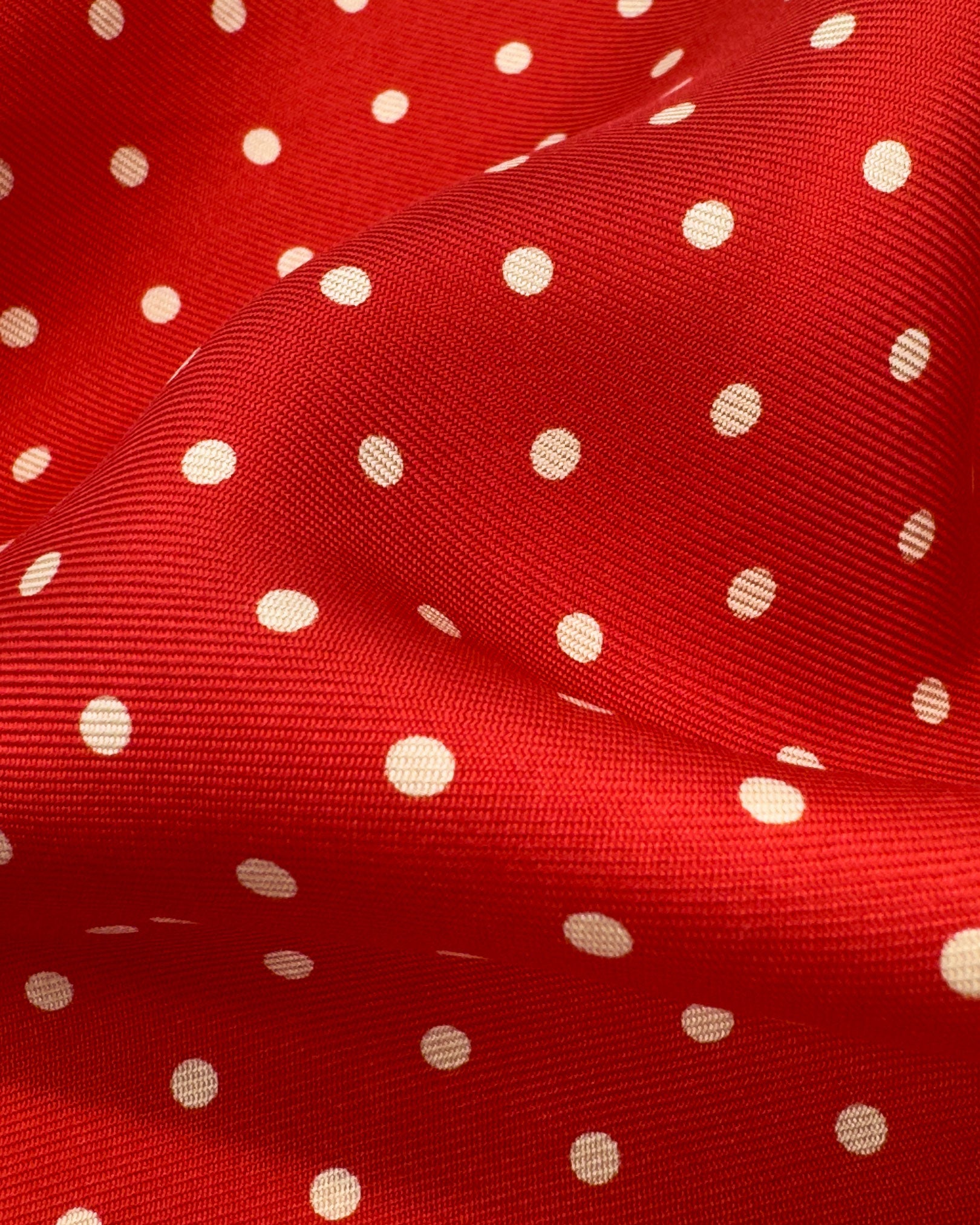 A ruffled close-up of the 'Hastings' pocket square, presenting a closer view of the white polka dots against the attractive lustre of the deadstock silk material. 