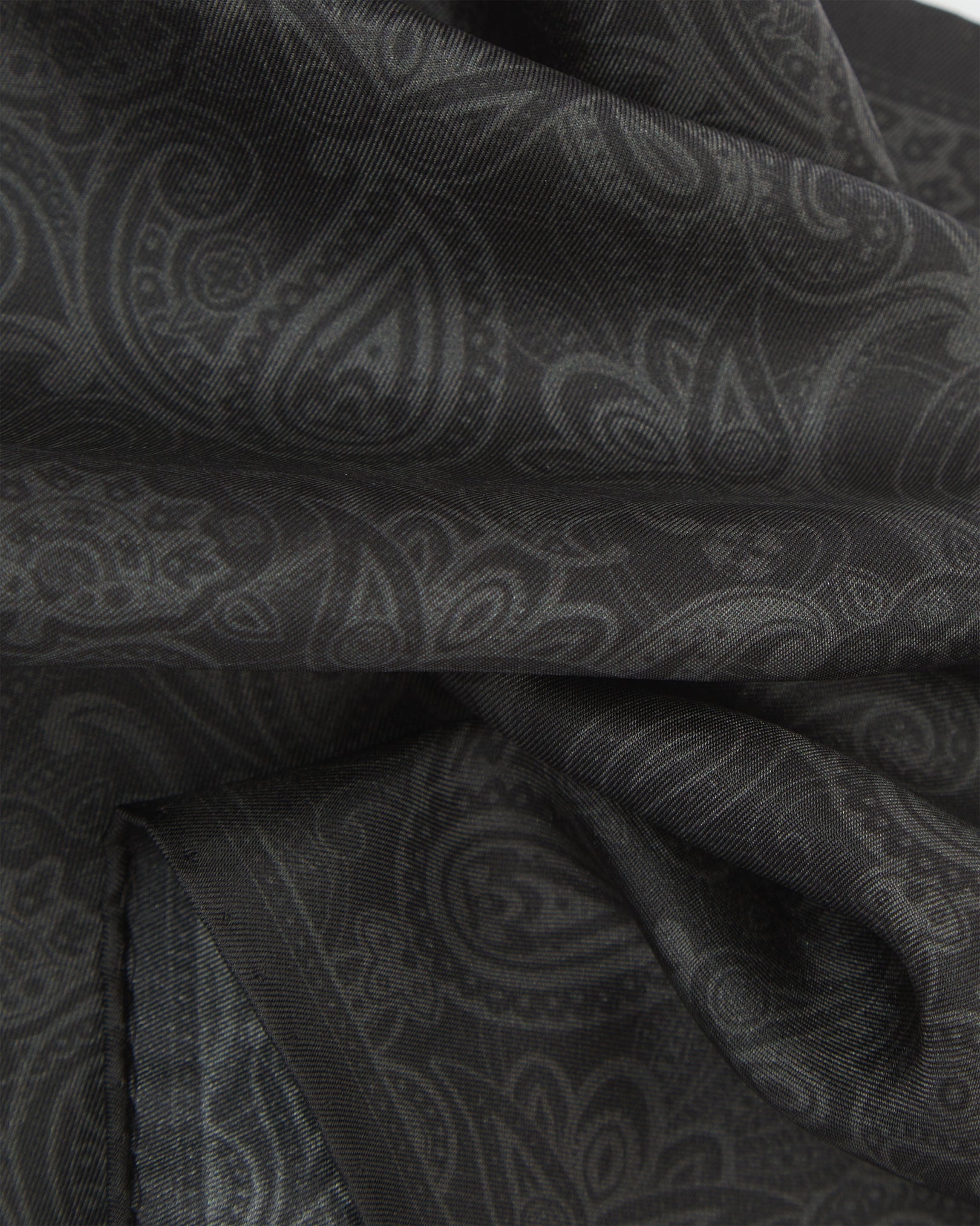 A ruffled close-up of the black silk pocket square from SOHO Scarves, showing the fine silk weave and subtle tonal paisley pattern in detail.