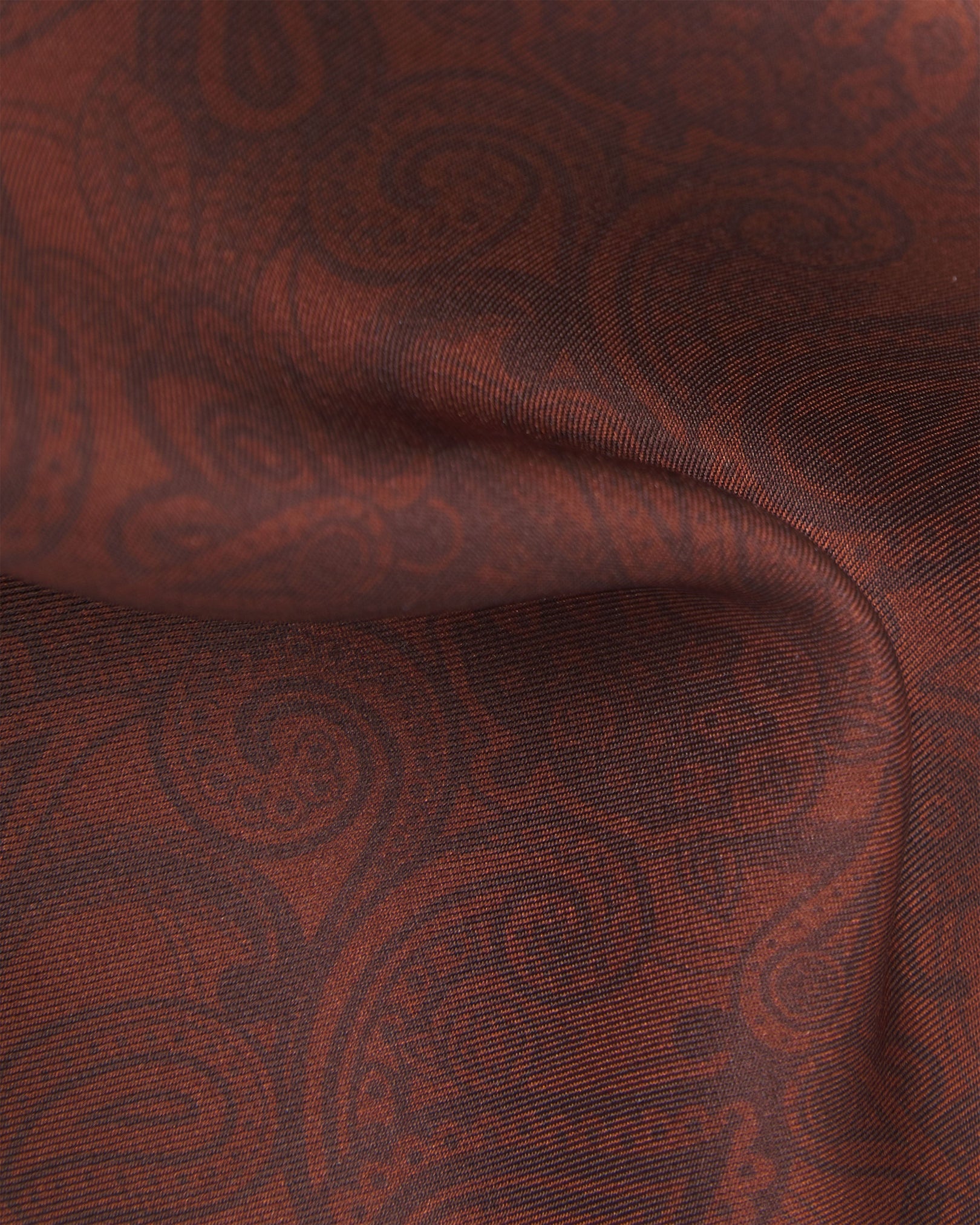 Close-up of the cocoa silk pocket square from SOHO Scarves, showing the detailed brown paisley pattern and the fine smooth silk weave.