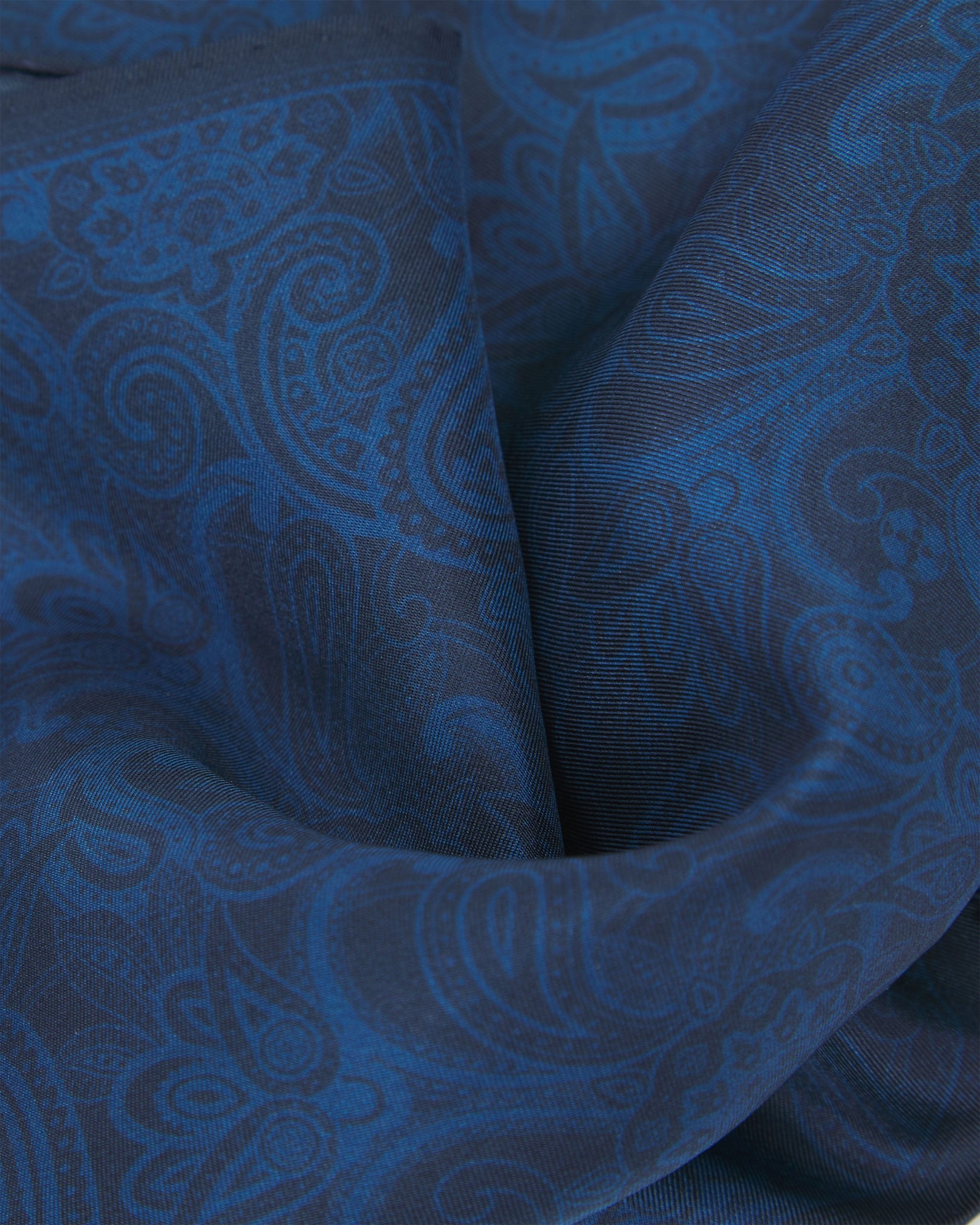 A ruffled close-up of the dark navy blue silk pocket square from SOHO Scarves, emphasizing the intricate paisley design and rich colour depth.