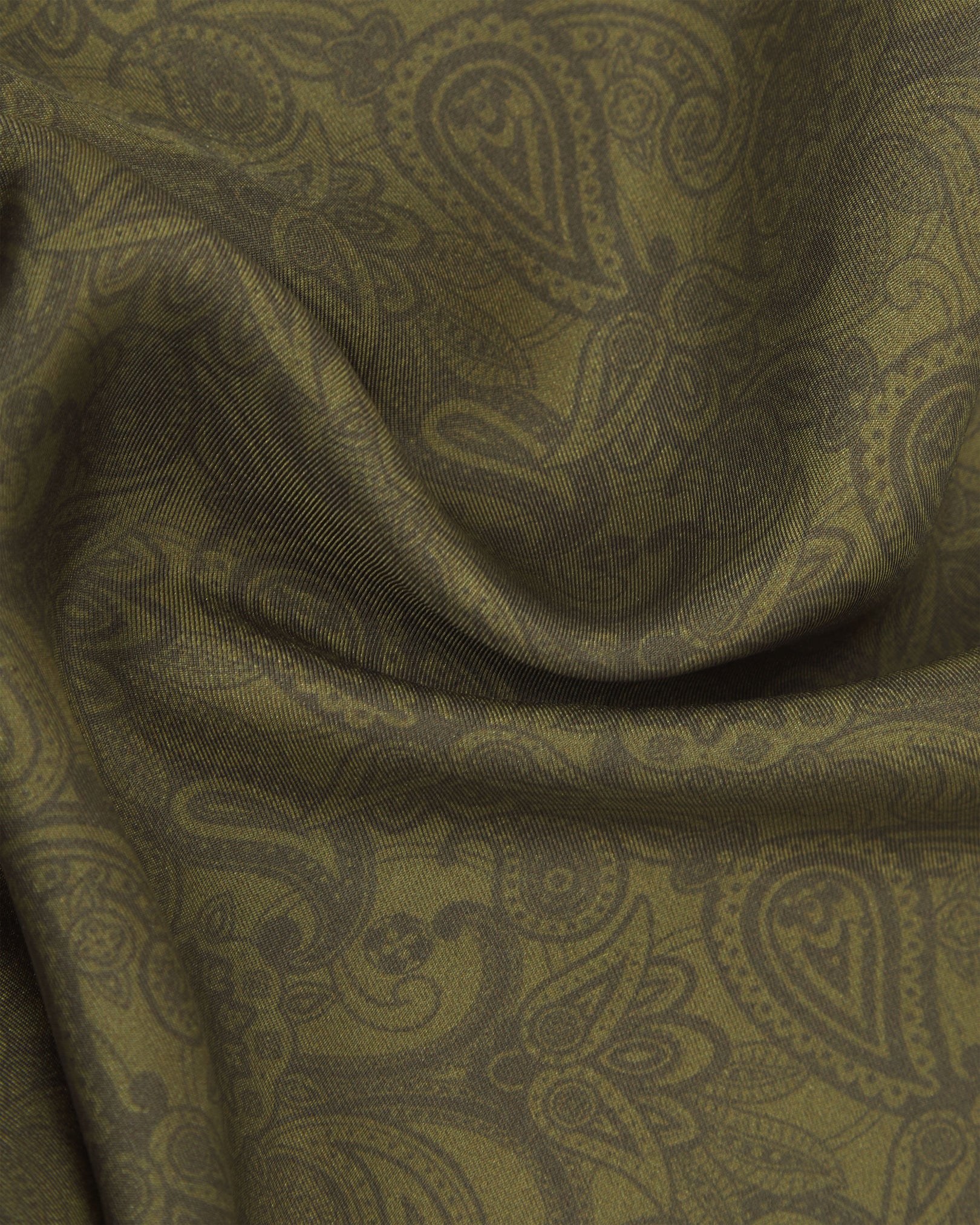 A ruffled close-up of the olive silk pocket square from SOHO Scarves, emphasizing the intricate paisley design and rich colour depth.