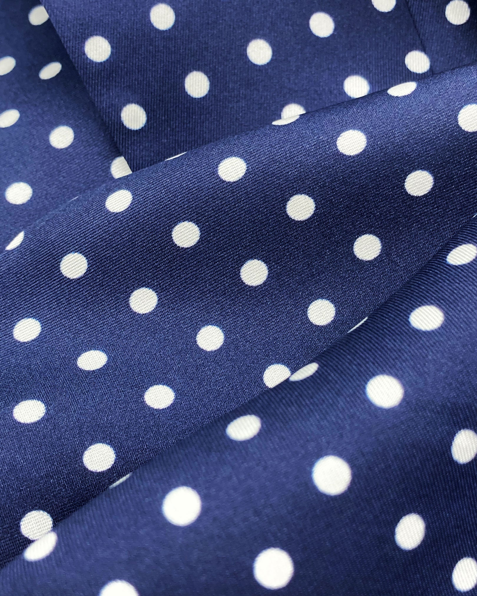 Ruffled close-up view of the 'Westminster' silk scarf, presenting a closer view of the polka dot design in navy-blue with white spots and subtle lustre of the silk material.