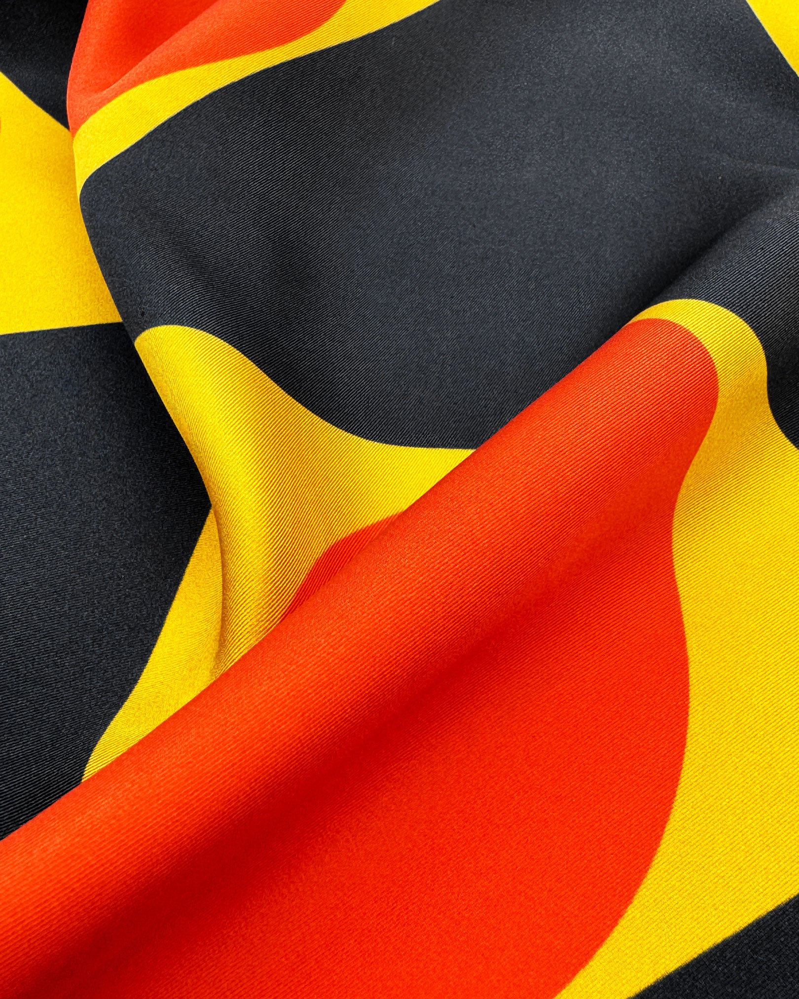 A ruffled close-up of the 'Dresden' silk scarf, presenting the attractive interplay of ochre-yellow, charcoal grey and orange.