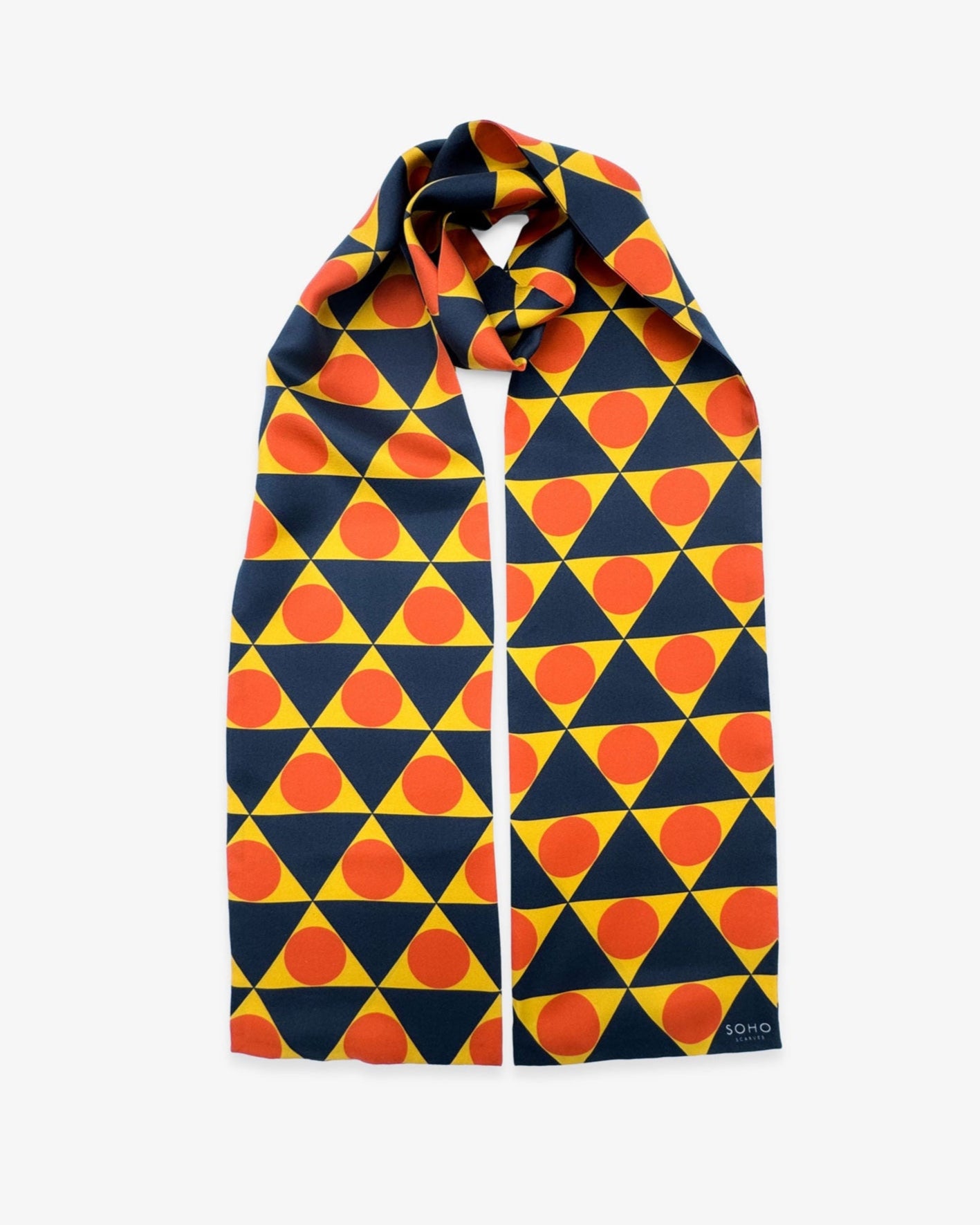 The 'Dresden' Bauhaus-inspired silk scarf looped with both ends parallel to effectively display the full repeat pattern of yellow, charcoal and orange triangular and circular forms.