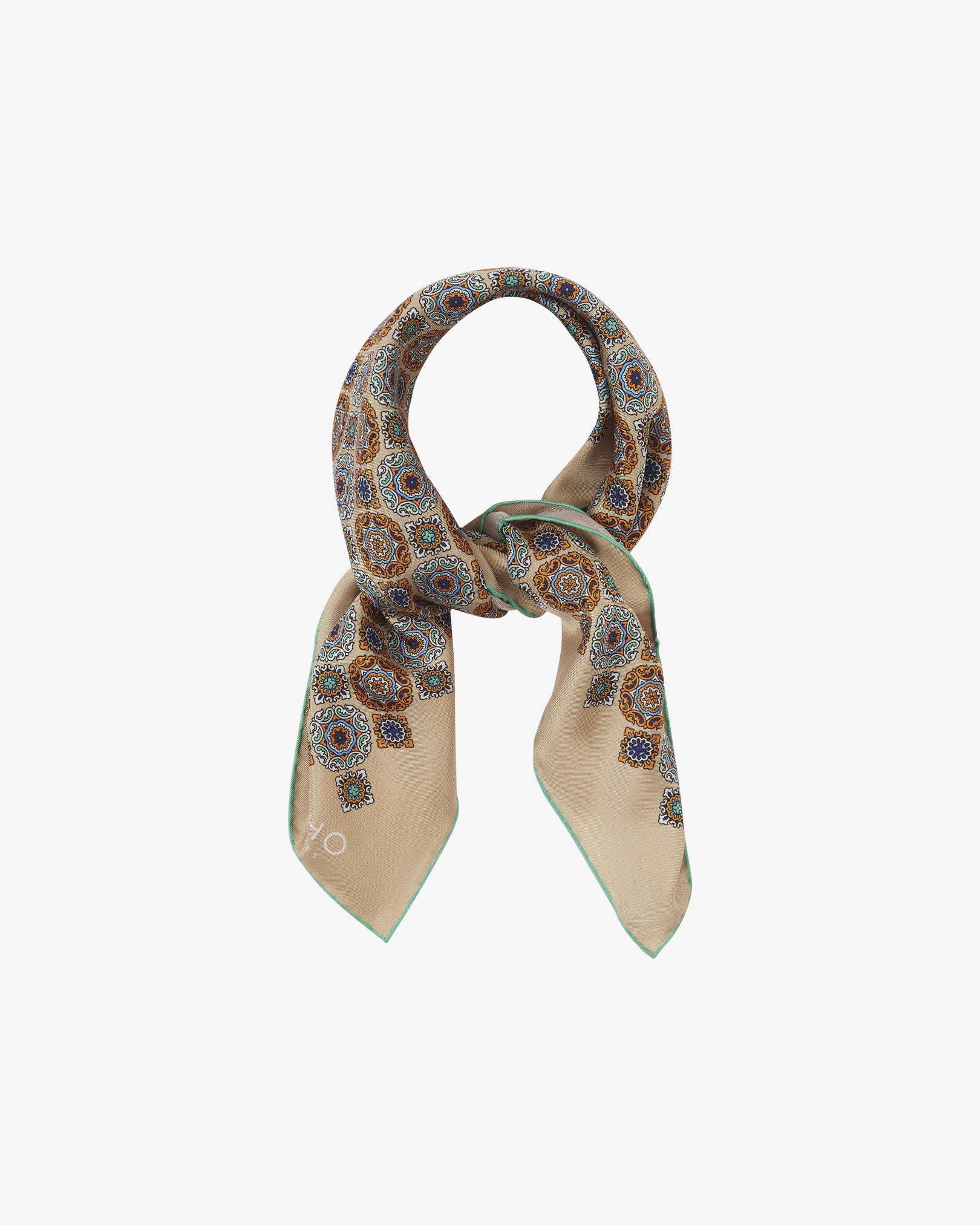 The 'Fitzrovia' neckerchief looped and knotted, revealing the ornate medallion design in navy, teal, and burnt orange against a warm hazelnut silk background.