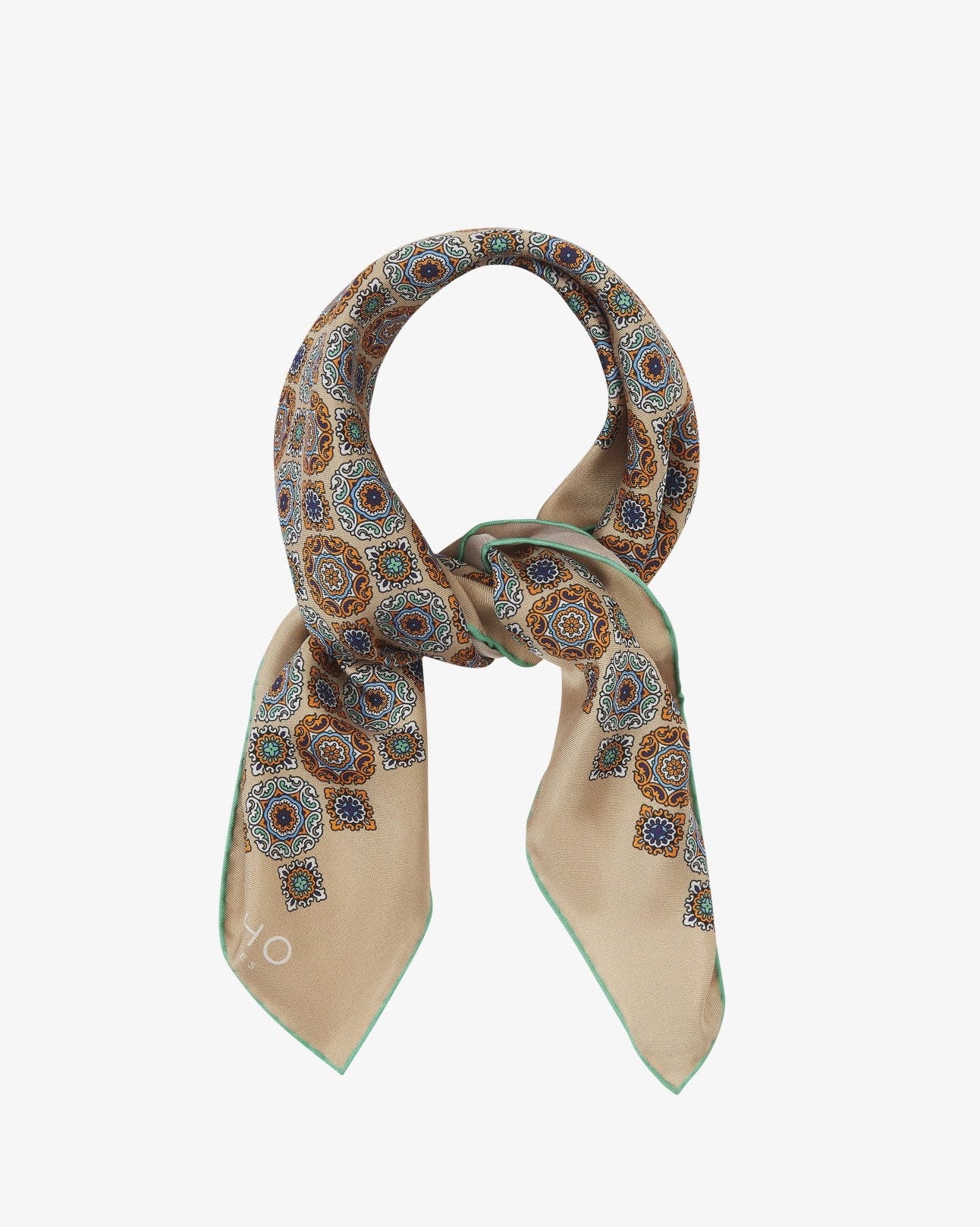 The 'Fitzrovia' neckerchief looped and knotted, revealing the ornate medallion design in navy, teal, and burnt orange against a warm hazelnut silk background.