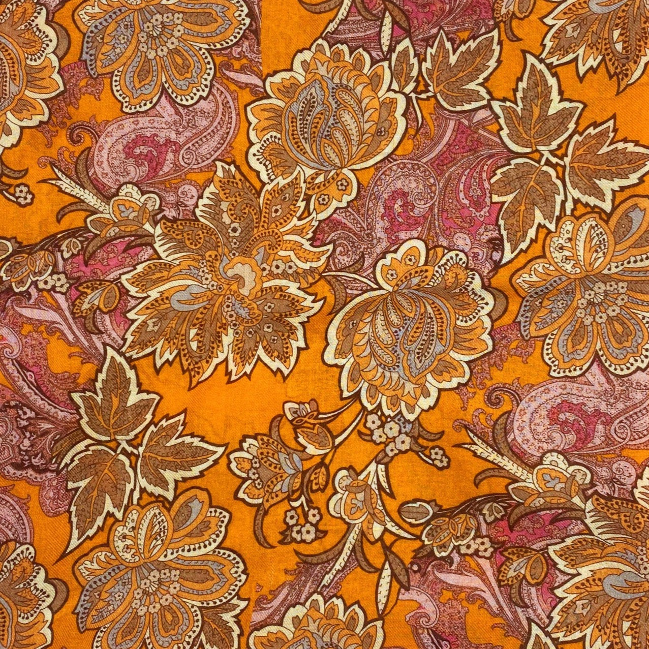A flat, folded view of 'The Niagra' bandana. Clearly showing the intricate floral and leaf patterns in various shades of orange and pink on a deep orange background.