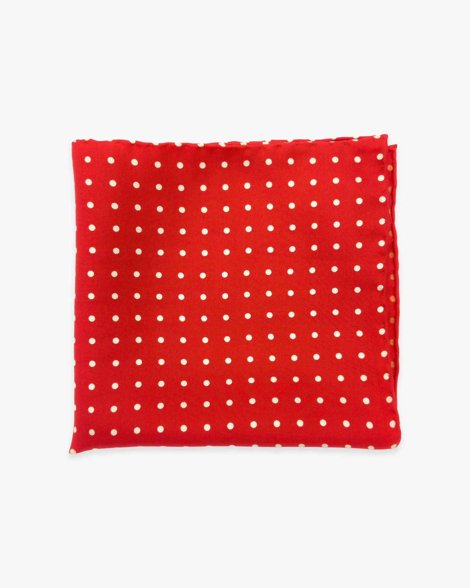 The 'Hastings' silk pocket square from SOHO Scarves UK collection. Folded into a quarter, showing the white polka dots against a bright red background.