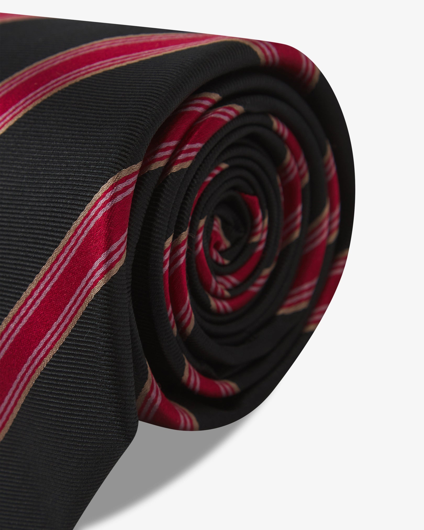 The 'Hutcherson Good Fortune' silk neck tie neatly coiled with a clear view of the silk weave and red, pink and gold striped pattern
