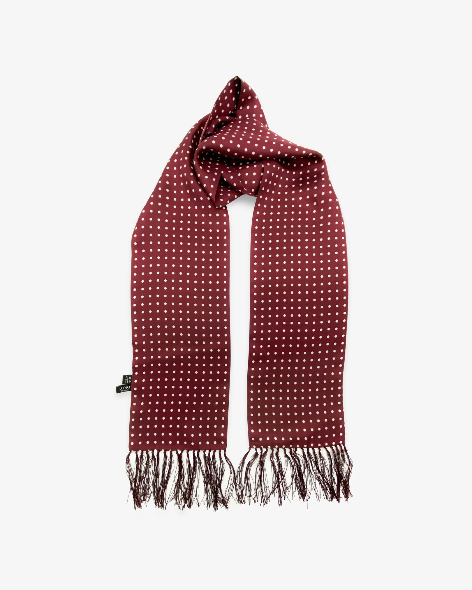 The Sapporo pure silk aviator scarf looped in middle with both ends parallel showing the polka dot design in deep maroon with white dots and matching 3-inch fringe.