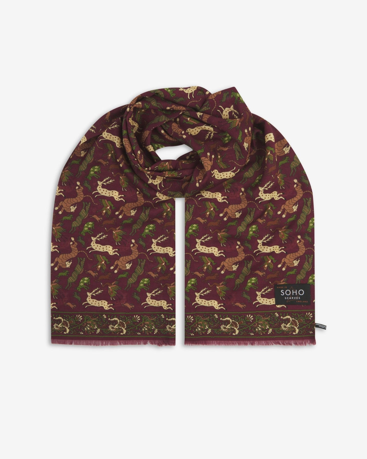 Premium burgundy silk-wool scarf with stylised woodland creatures. Unravelled and looped in the middle, presenting slightly longer and wider scarf dimensions, ornate border, eyelash fringing and ‘Soho Scarves’ label.