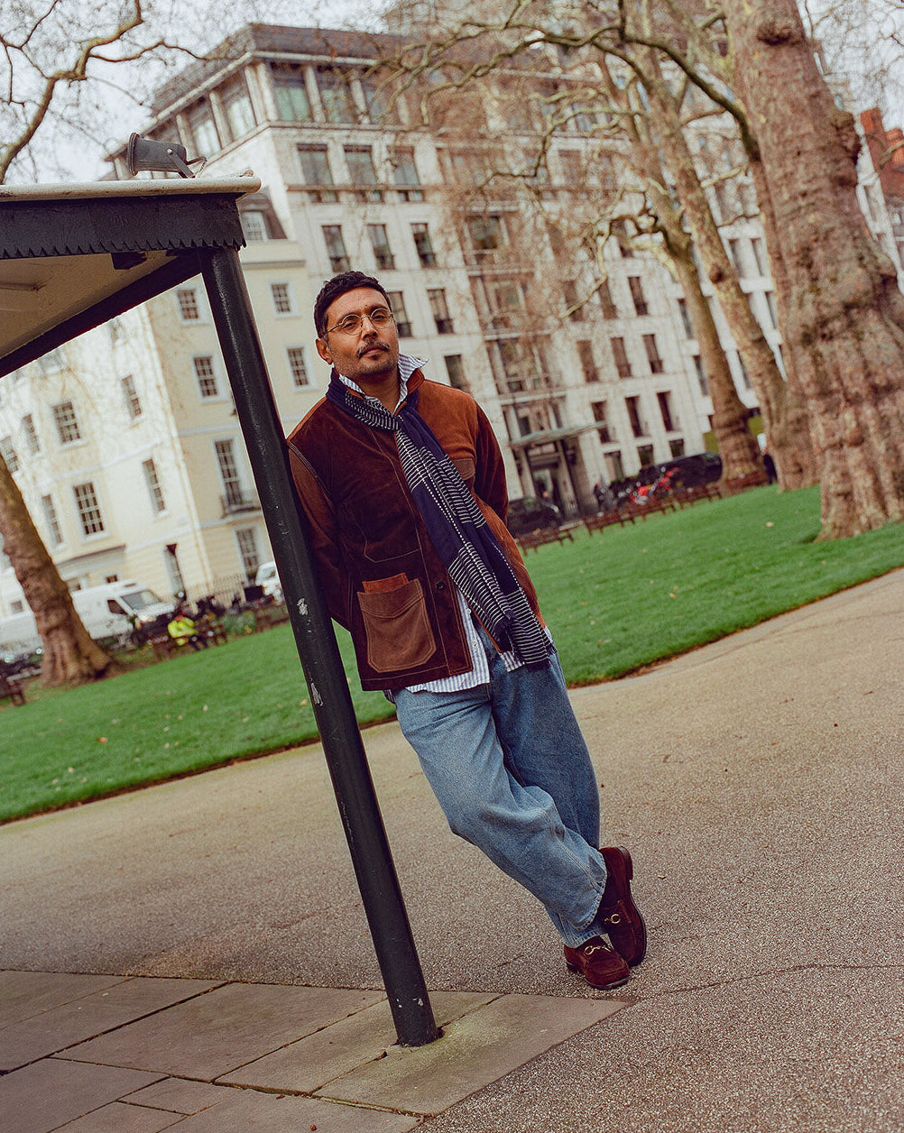 Man leaning against a black metal railing in an urban park setting