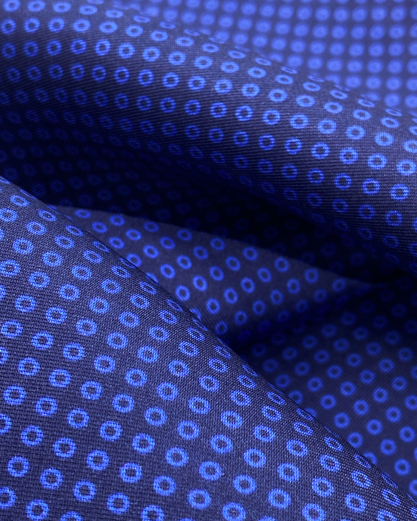 A ruffled close-up of the 'Nakano' silk scarf, presenting a closer view of the geometric small pale blue circles against the deep blue background.
