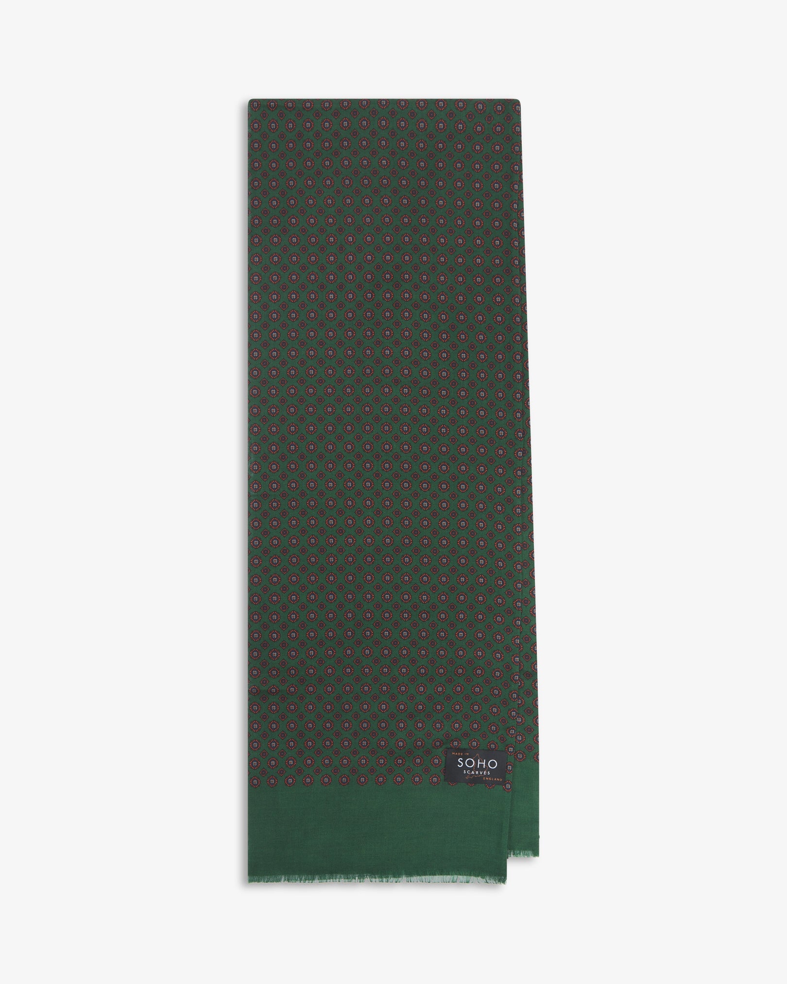 English-made silk and wool scarf arranged in a rectangular shape, displaying the repeating floral-inspired geometric forms with green eyelash fringing.