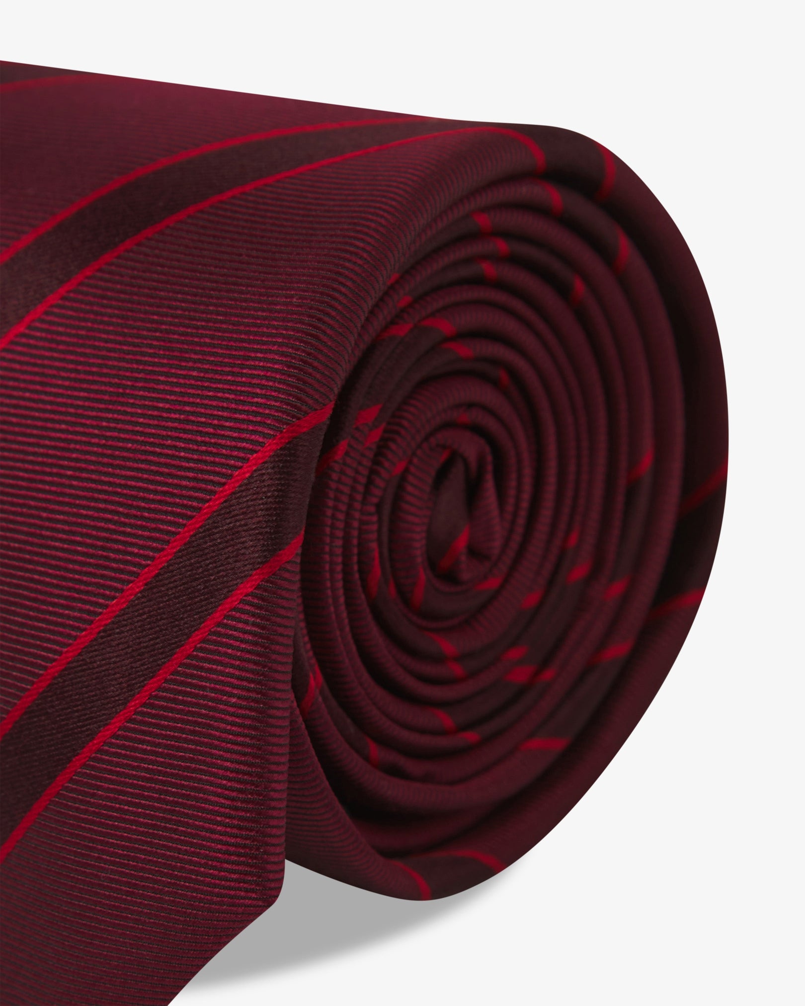 The 'Sanders Good Fortune' silk neck tie neatly coiled with a clear view of the silk weave and red stripes.