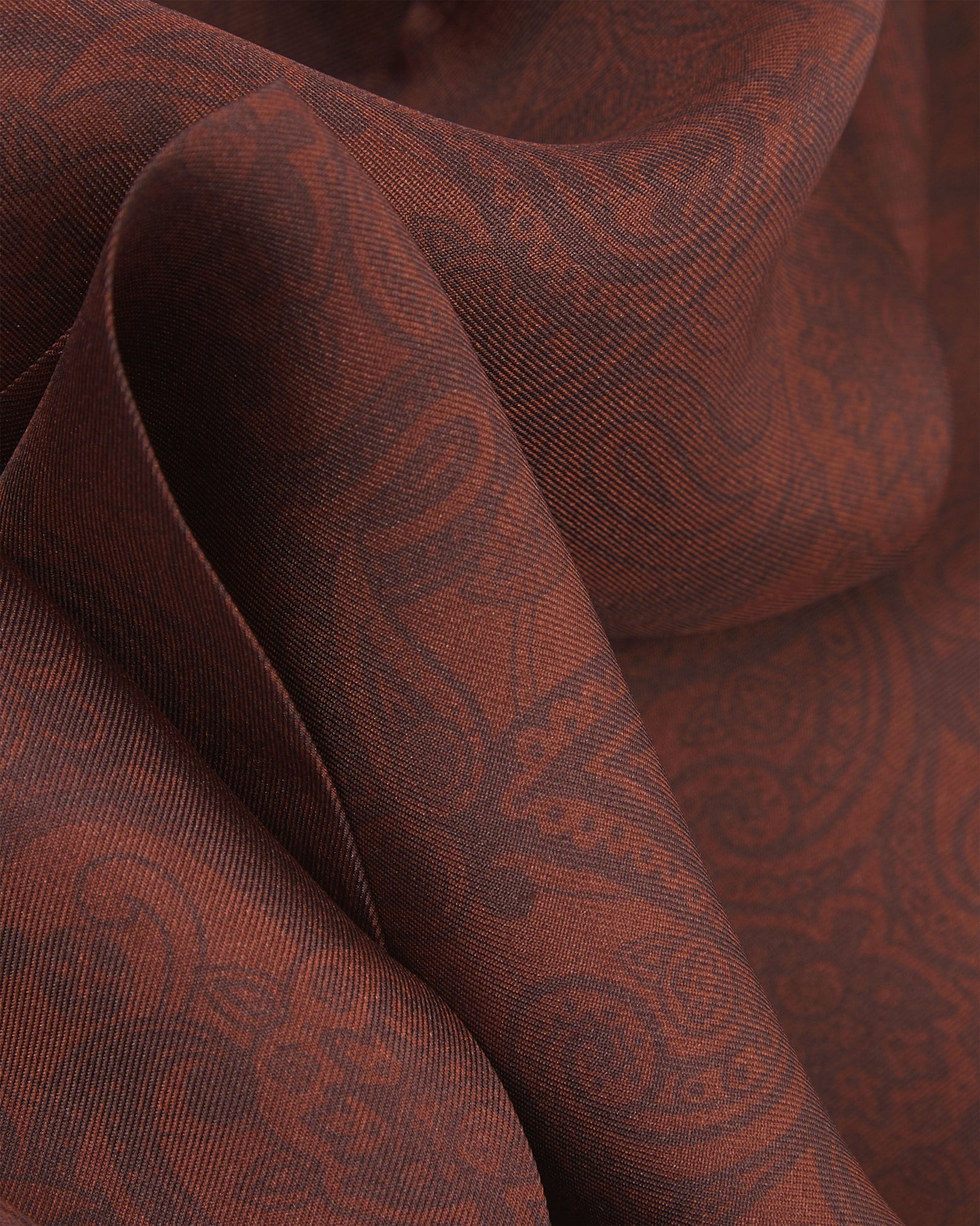 A ruffled close-up of the 'Tonal Paisley' cocoa silk scarf, capturing the layered texture and warm brown paisley design woven into the rich cocoa-toned silk.