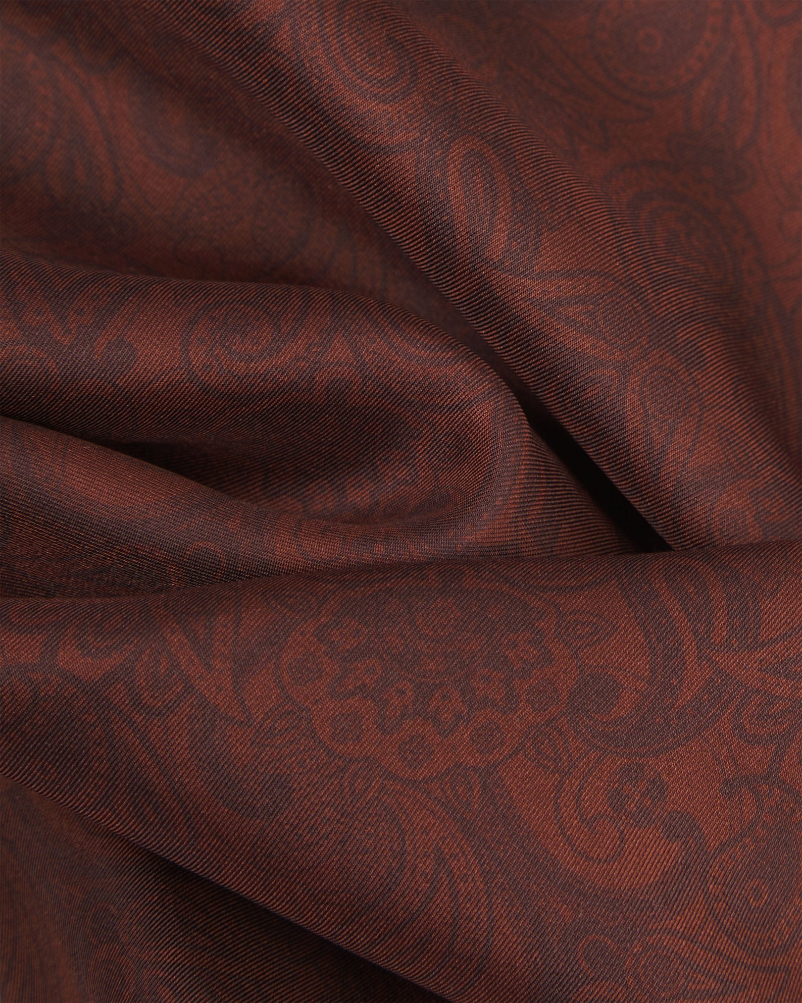 Ruffled close-up view of the 'Tonal Paisley' cocoa silk scarf, showing the textured weave and intricate warm brown paisley detailing across the silk surface.