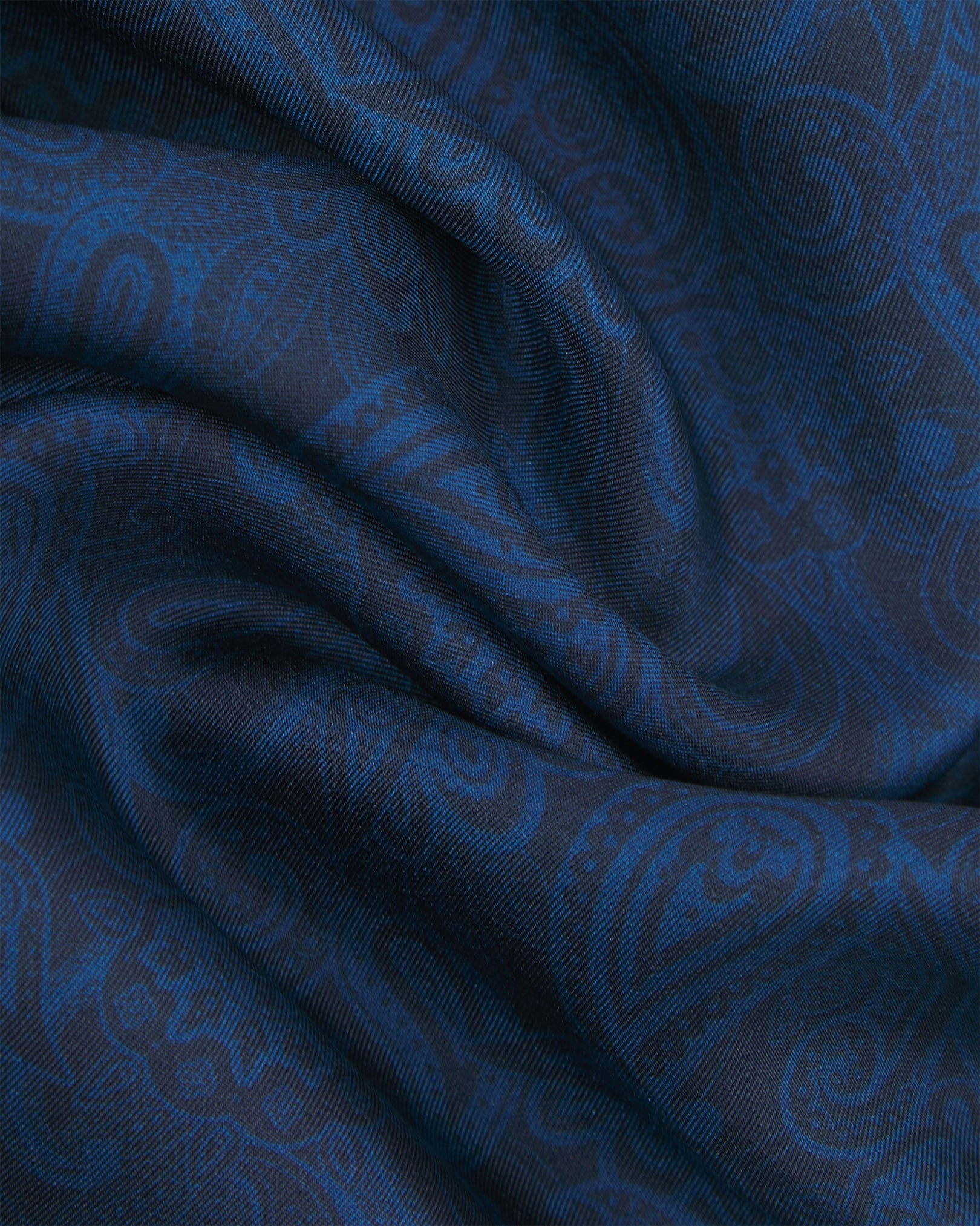 Ruffled close-up view of the 'Tonal Paisley' dark navy silk scarf, showing the smooth texture and detailed layering of midnight and cobalt paisley patterns on the silk surface.