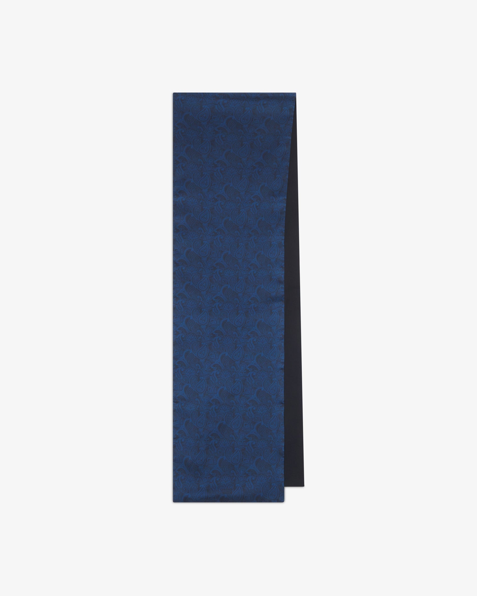 The 'Tonal Paisley' dark navy wool-backed silk scarf folded into a rectangular shape, displaying the full deep blue paisley pattern on the silk side and a sliver of the dark wool underside.