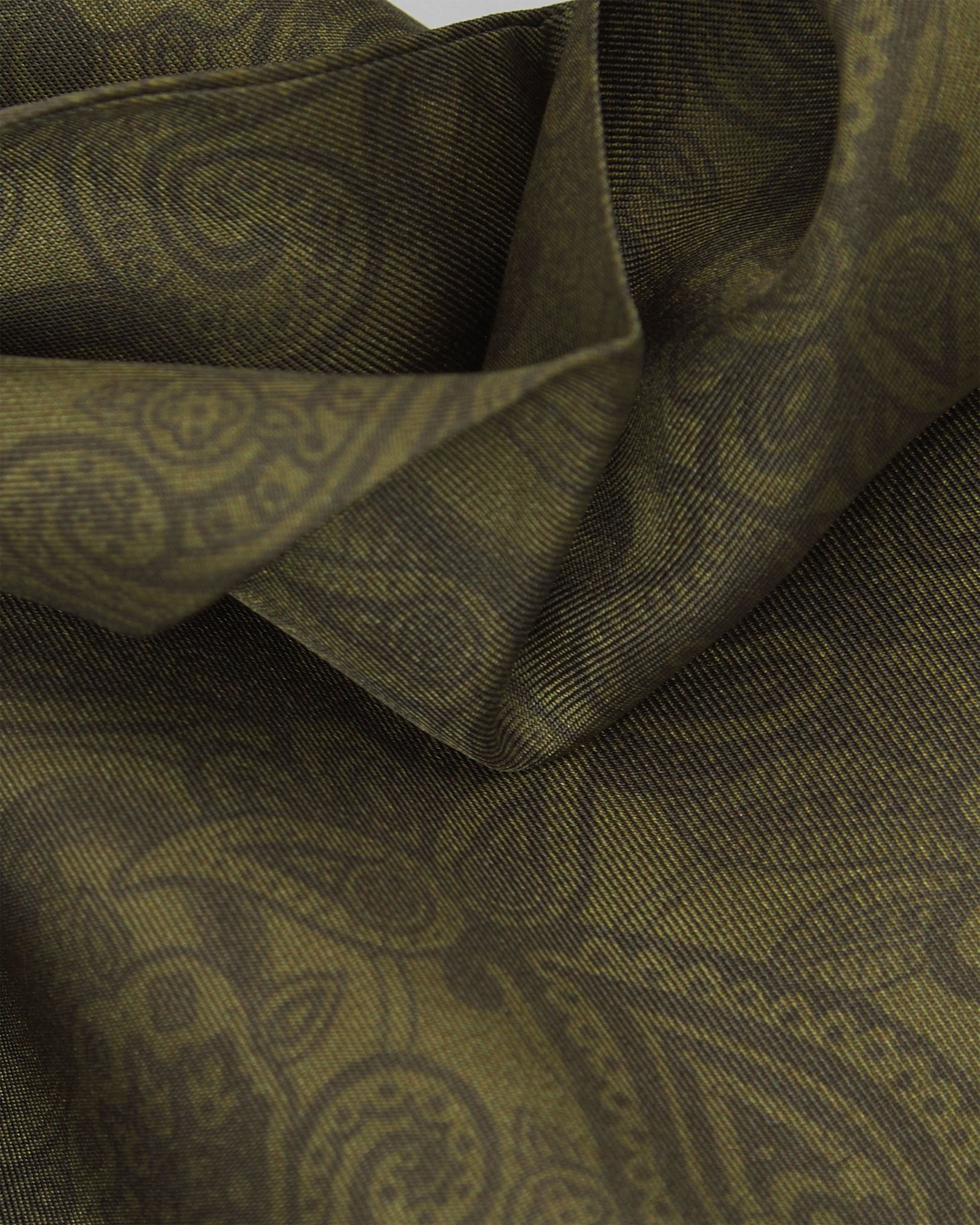 A ruffled close-up of the 'Tonal Paisley' olive silk scarf, highlighting the layered weave and subdued green paisley pattern on a soft olive backdrop.