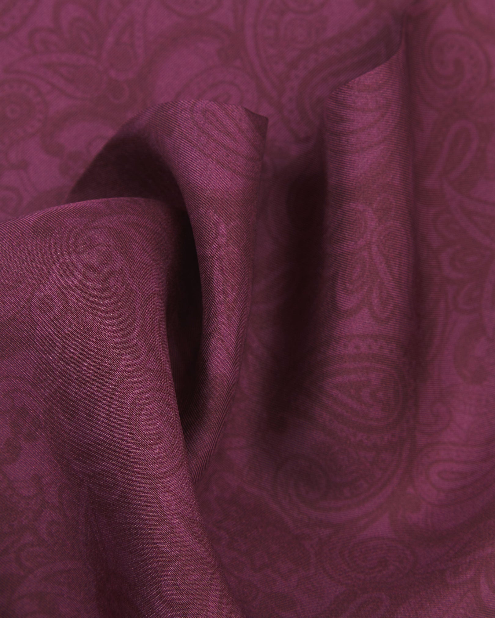 A ruffled close-up of the 'Tonal Paisley' purple silk scarf, revealing the soft drape and layered plum paisley design woven into the violet-toned silk.