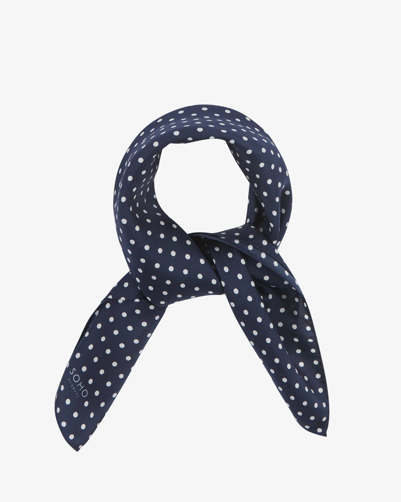 Square scarf rolled into a loop, showing the fabric sheen of the classic dark-blue and white spotty silk fabric