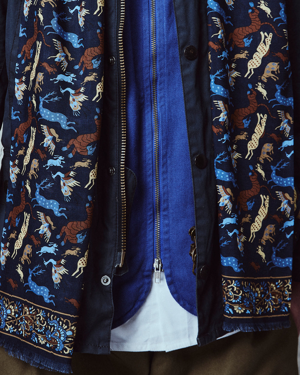 Close-up of man wearing the English-made, 'Woodland Creatures in Airforce Blue' silk and wool scarf, with focus on the blue and brown woodland creature motifs and floral border.