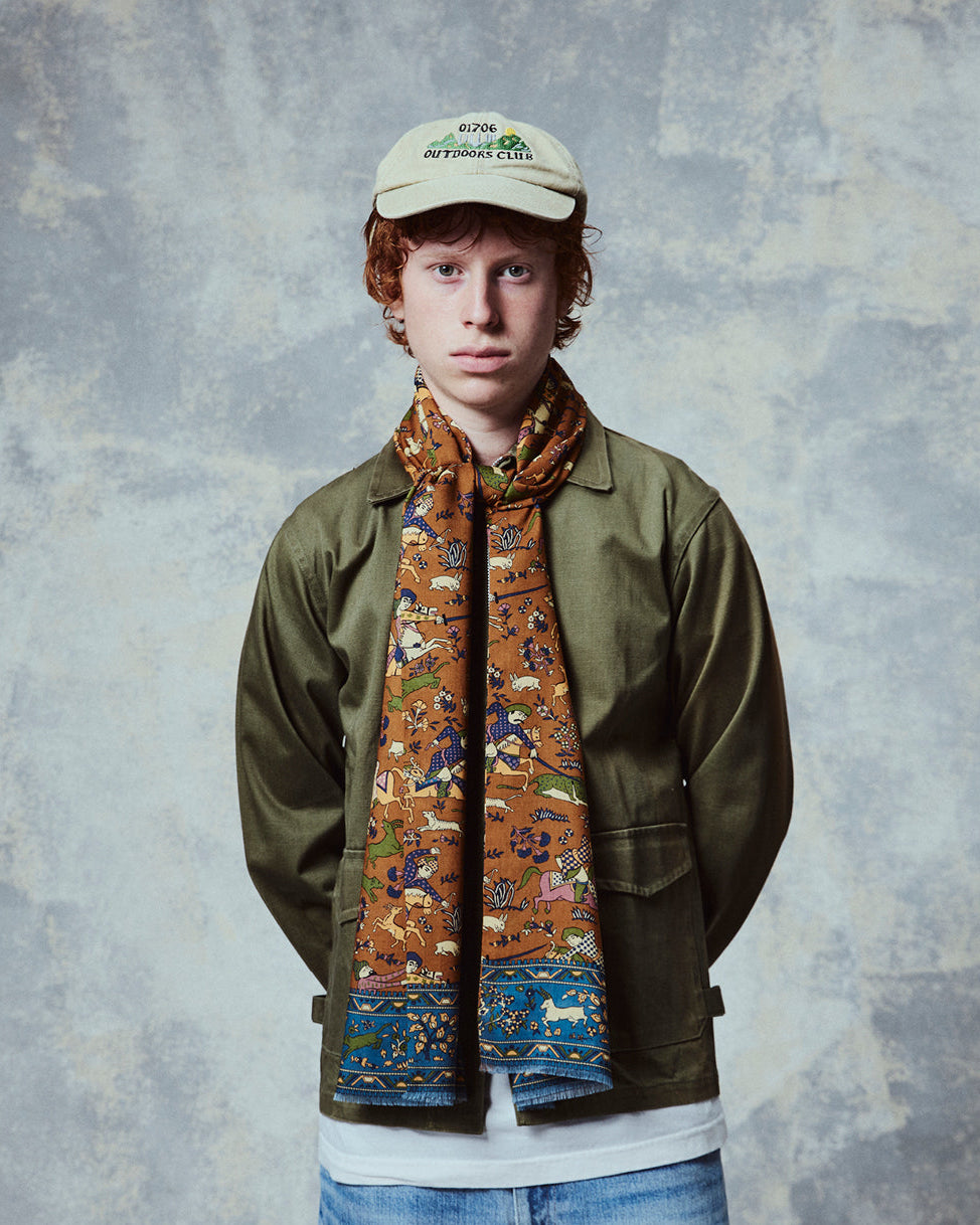 Top-half view of man wearing the English-made, 'Hunters in Dull Gold' silk and wool scarf from Soho Scarves.