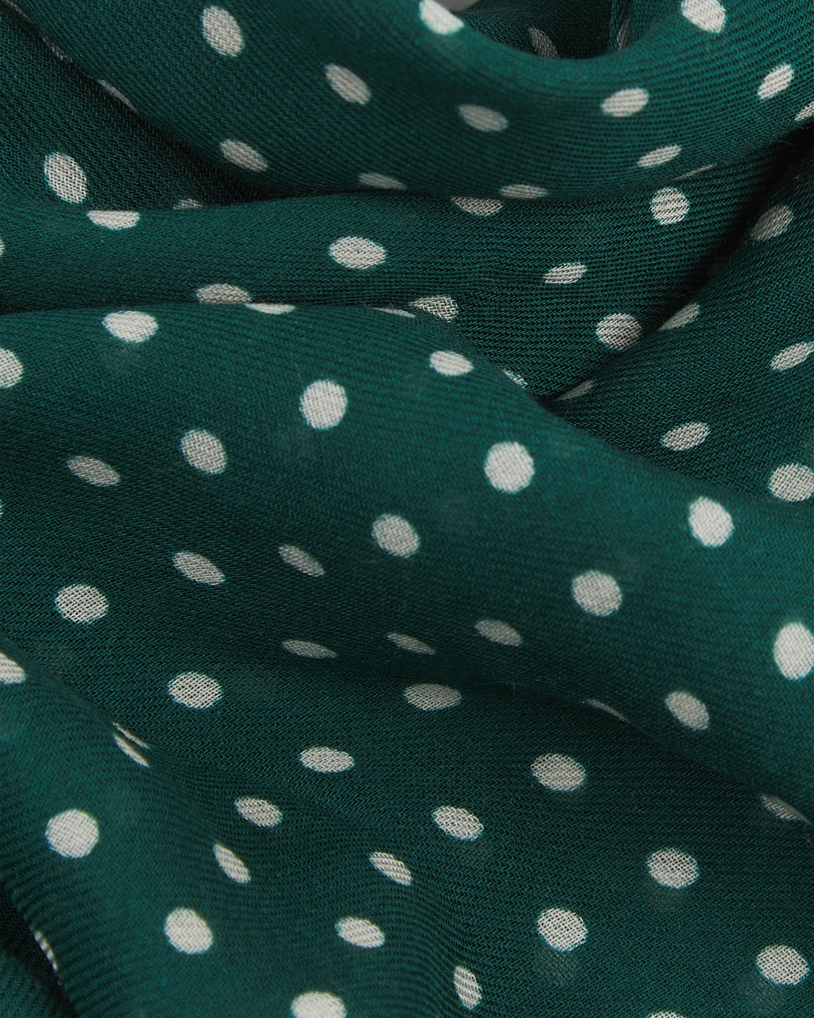 A ruffled close-up of The Westminster RG bohemian wide scarf, showing the soft modal and wool blend fabric with evenly spaced white polka dots on a British racing green background.