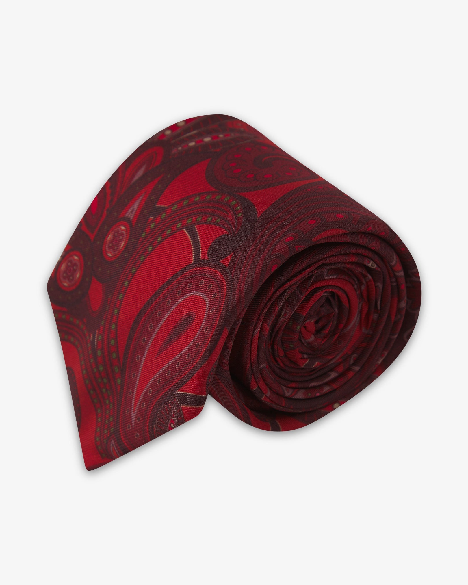 Focus on the tip of the 'Windermere Good Fortune' silk neck tie. Showing the dark red paisley motifs and the remaining tie length neatly coiled.