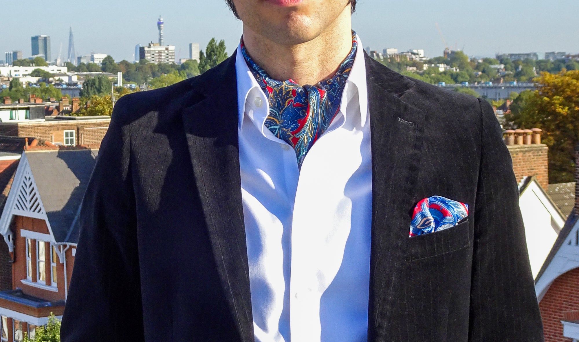 Mid section view of man wearing red and blue paisley scarf with white shirt and blazer