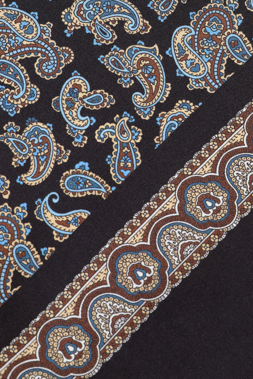 Angled view of the Dylan silk scarf showing the multicoloured and intricate paisley patterns and border.
