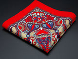 Pure wool 'Kopli' pocket square folded into a quarter, clearly showing the heart-shaped paisley motifs and ornate blue border on a bright red ground.
