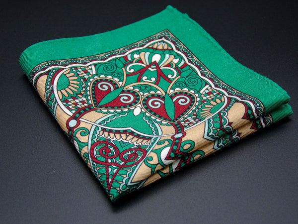 Pure wool 'Mustamae' pocket square folded into a quarter, clearly showing the heart-shaped paisley motifs and ornate green border on a green ground.
