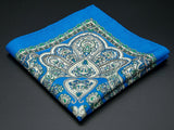 Pure wool 'Nomme' pocket square folded into a quarter, clearly showing the heart-shaped paisley motifs and ornate green border on a blue ground.