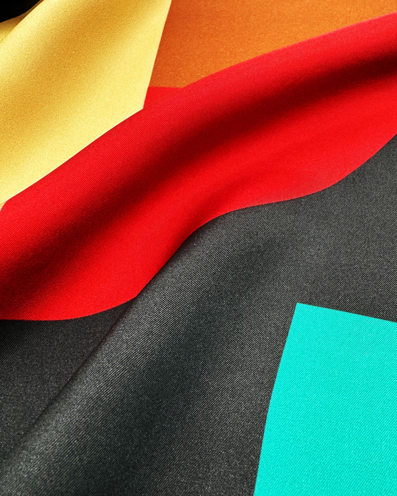 A ruffled close-up of the 'Berlin' silk neckerchief, presenting the interplay of the Bauhaus inspired palette.