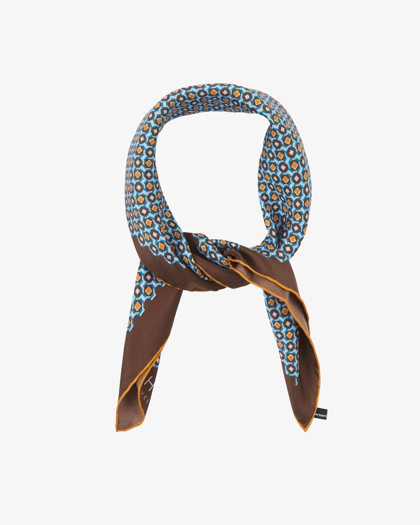 The 'Berwick' neckerchief looped and knotted, showcasing the blue, amber, and cream geometric pattern set against deep walnut silk, with a flash of the golden border.