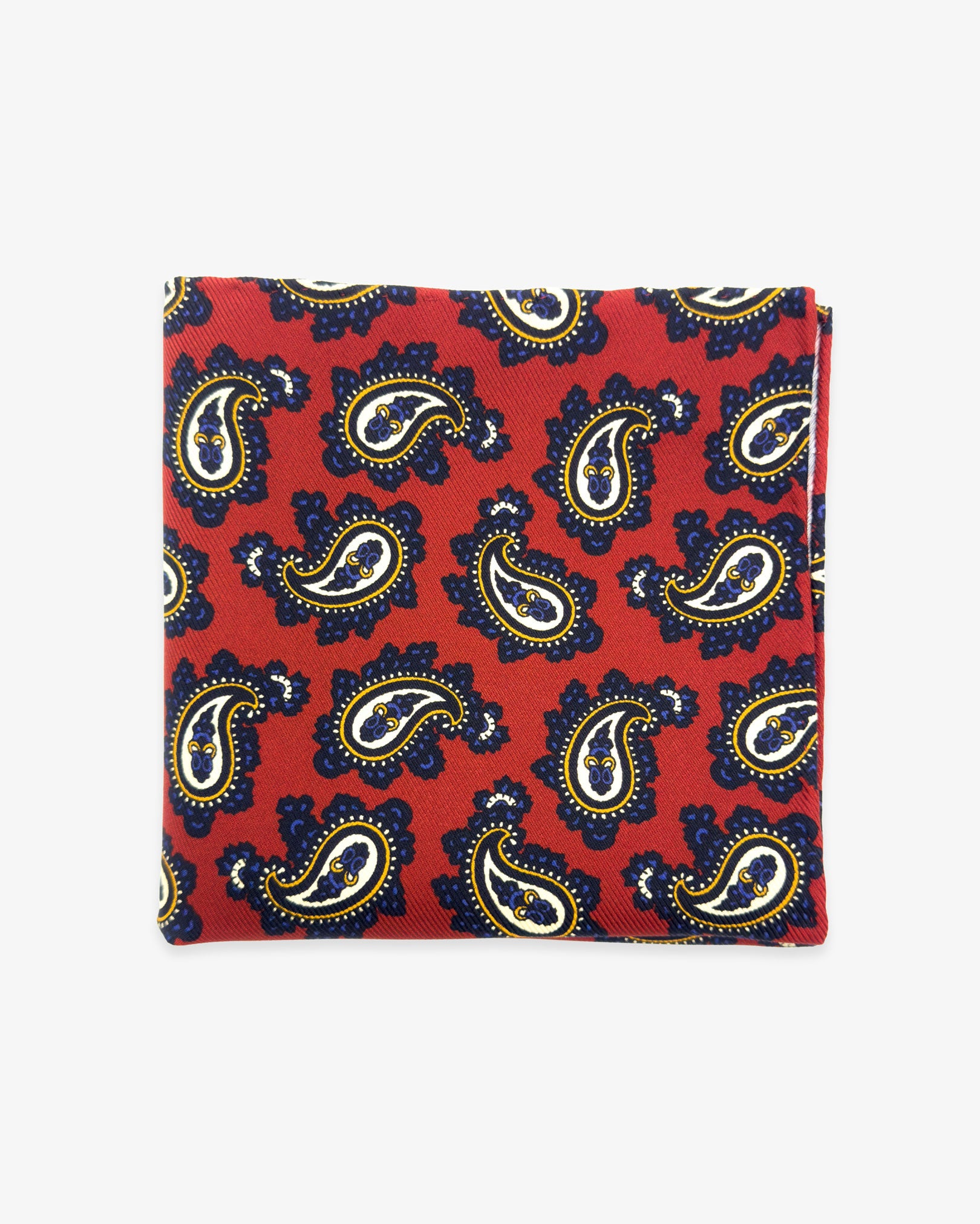 The 'Binham' silk pocket square from SOHO Scarves UK collection. Folded into a quarter, showing the classic paisley patterns against a red background.