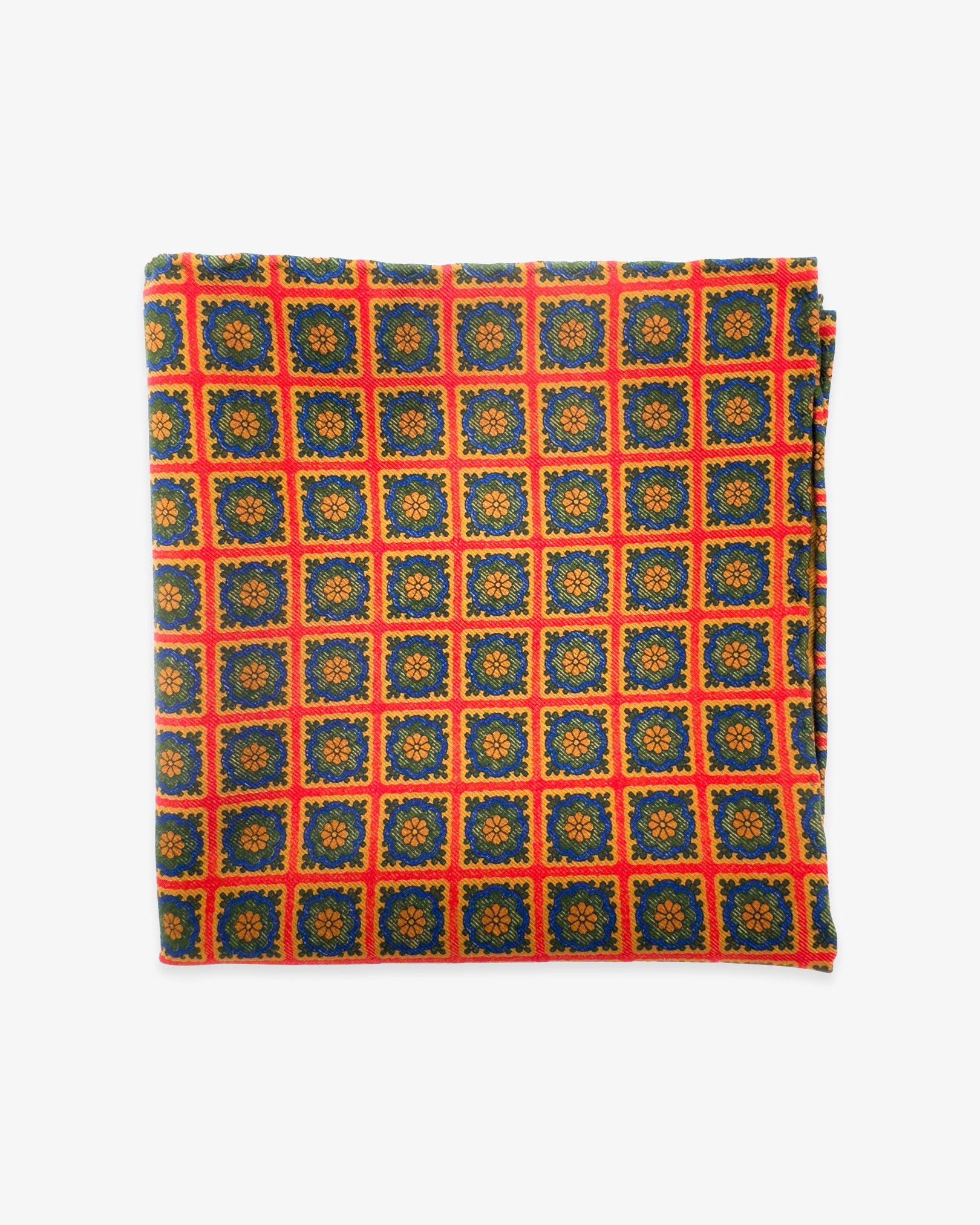 The 'Bolsover' silk pocket square from SOHO Scarves UK collection. Folded into a quarter, showing the individual blue, green and orange floral squares against a red-orange background.