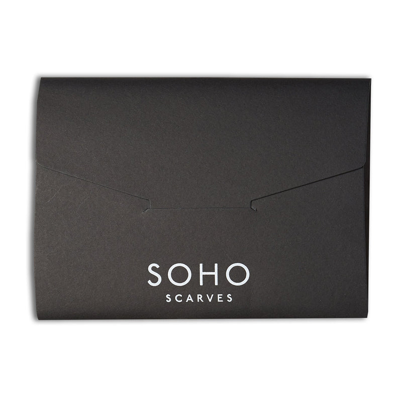 Branded black gift box from Soho Scarves with a closed, re-sealable flap. The gift box is sitting horizontally on a bright white background.