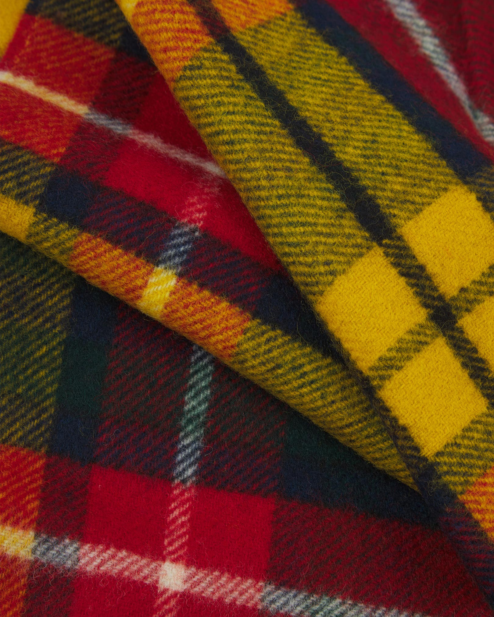 Ruffled close-up view of the UK-made, pure Merino wool 'Highlands tartan Buchanan' scarf, presenting a closer view of the red, yellow, and navy interlocking tartan pattern.