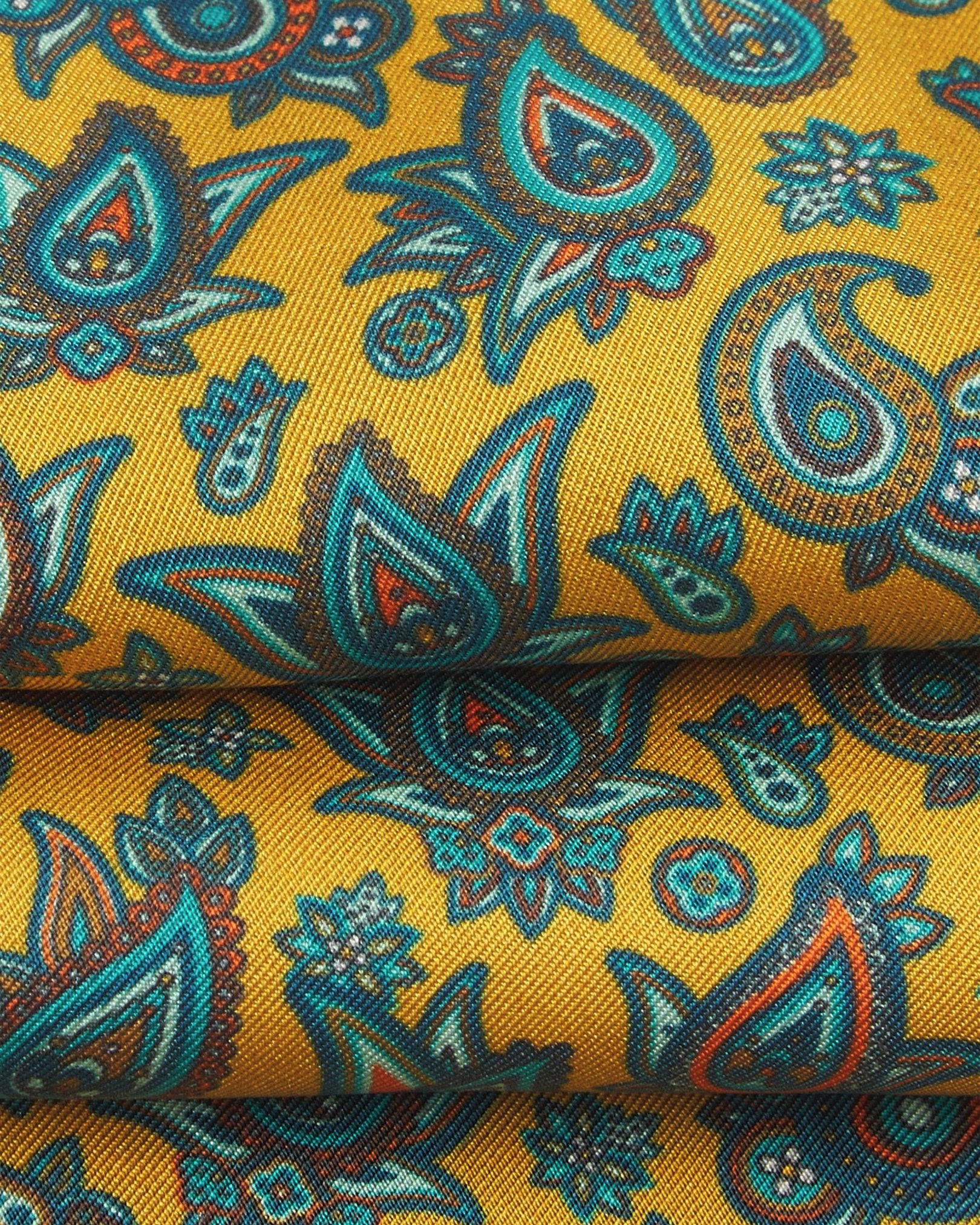 A ruffled close-up of the 'Buttermere' gold silk aviator scarf, presenting the overlapping elements of blue, blue-green, orange, and yellow paisley patterns.